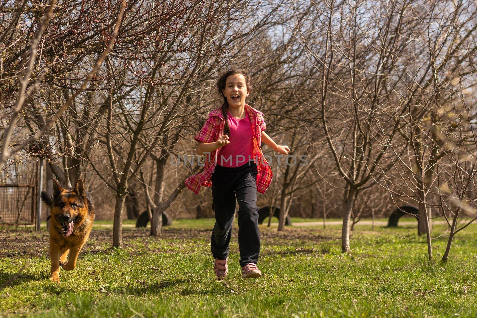 little girl running fast with a shepherd in the park.