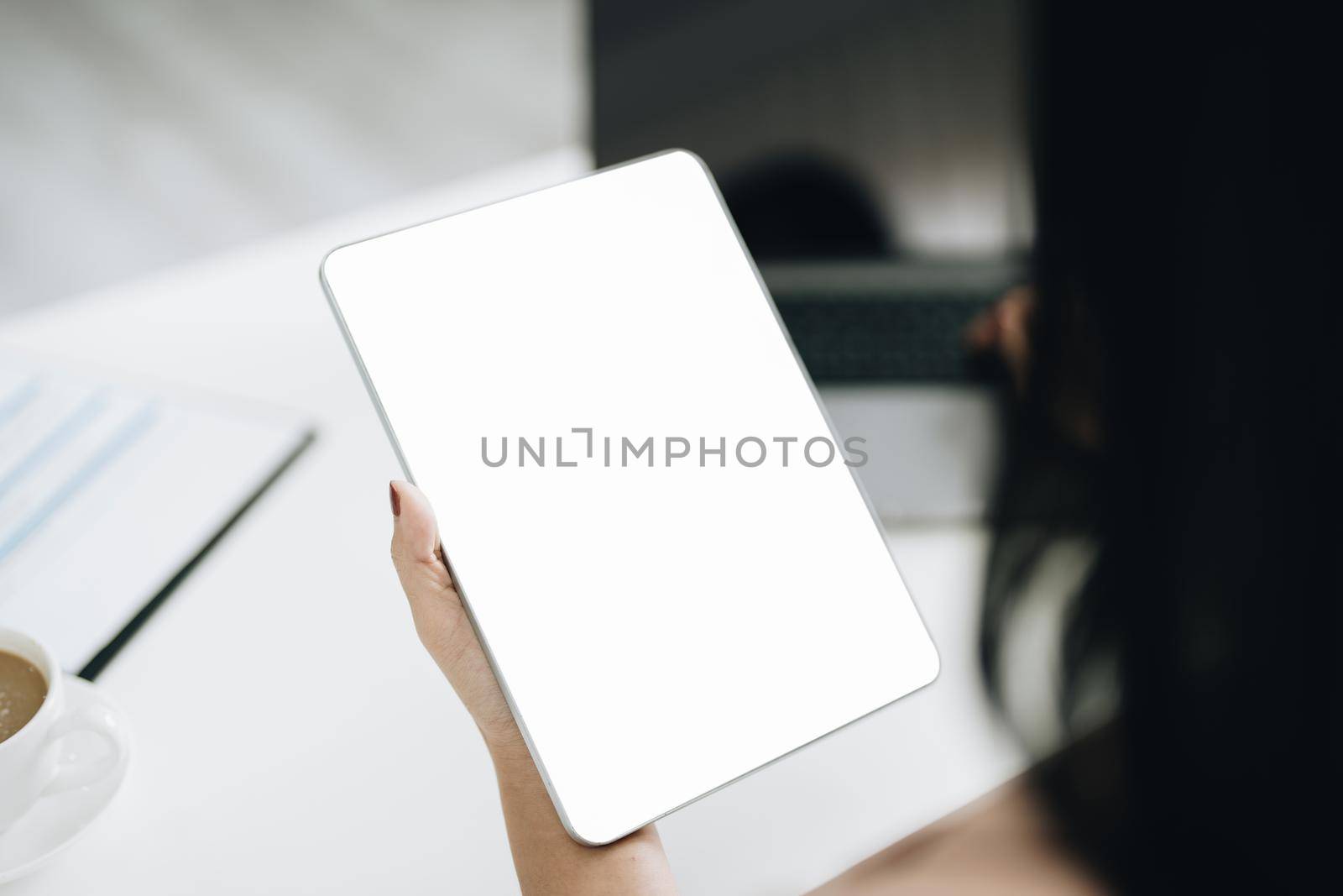 Young woman using work from home tablet to avoid the risk of contracting coronavirus in the company at work, the blank space on the tablet computer screen can insert text. by Manastrong