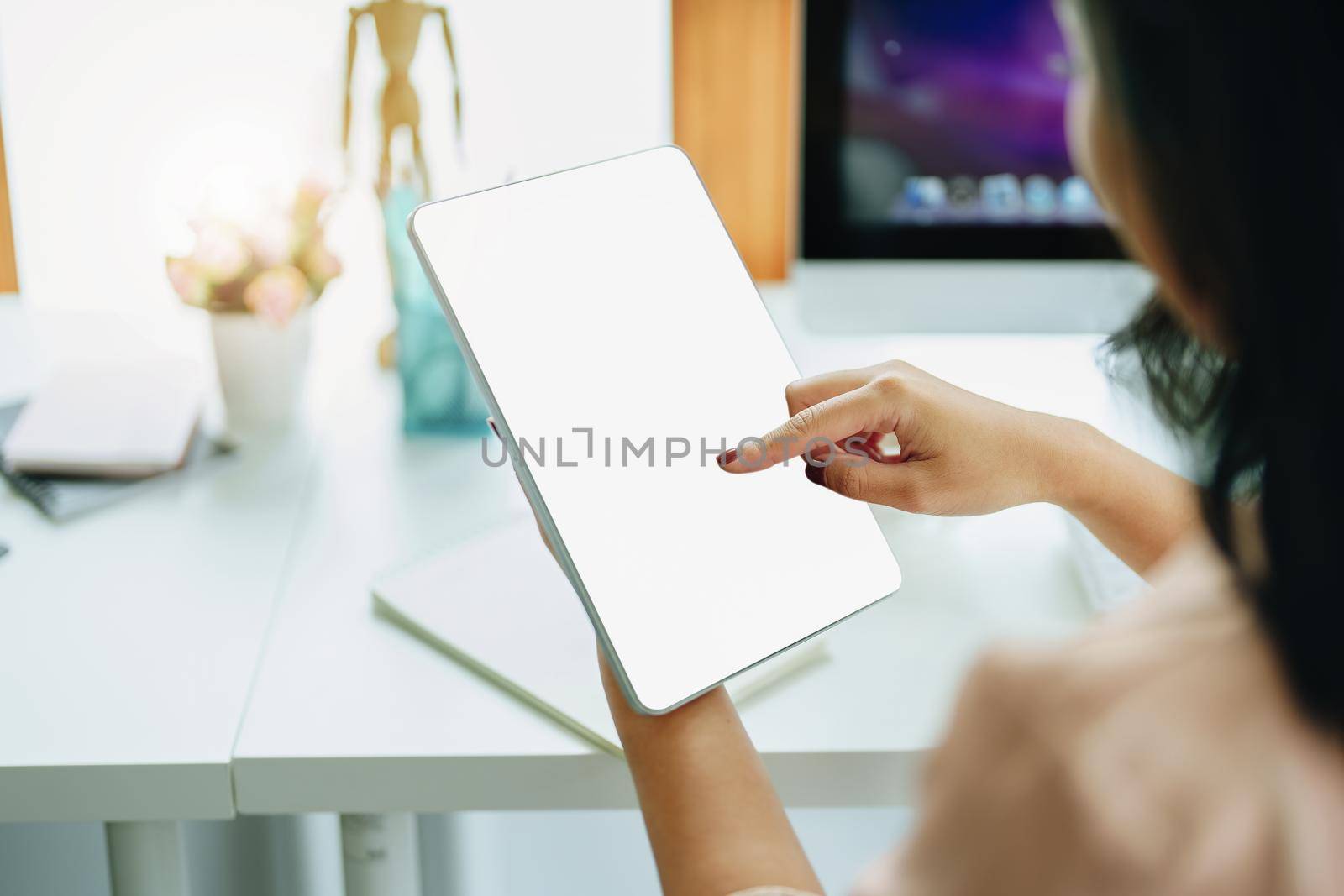 Young woman using work from home tablet to avoid the risk of contracting coronavirus in the company at work, the blank space on the tablet computer screen can insert text. by Manastrong