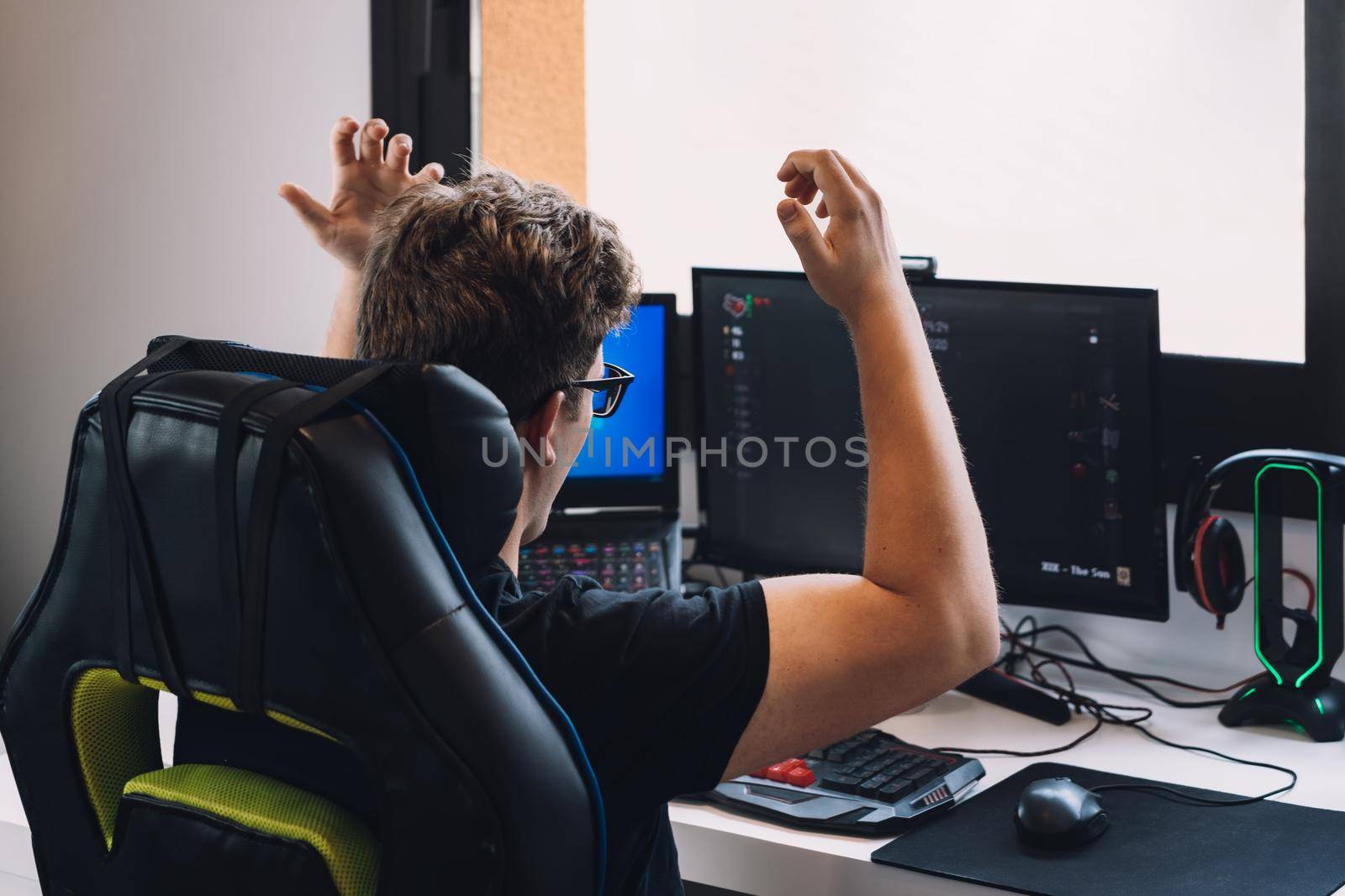 young blond man happily celebrating winning a video game on his computer. by CatPhotography