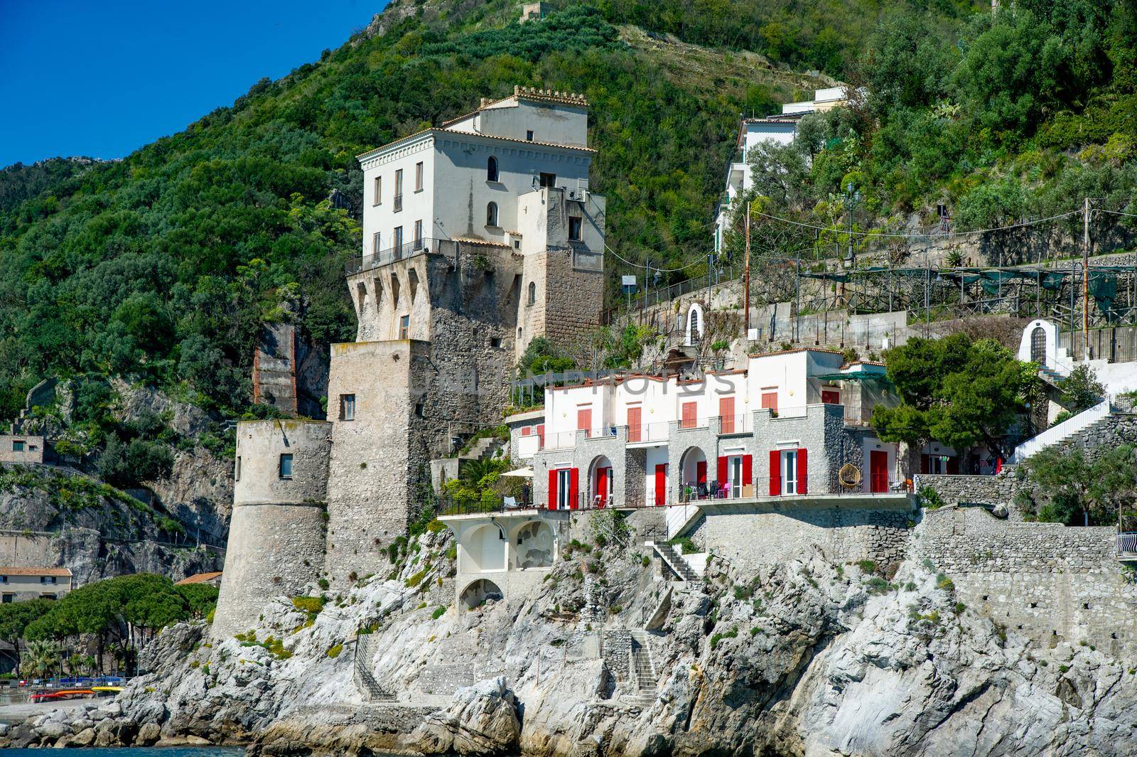 Beautiful view, of small haven of Amalfi village with small beach and colorful houses located on rock. Tops of mountains on Amalfi coast, Salerno, Campania, Italy blue sky and beautiful weather