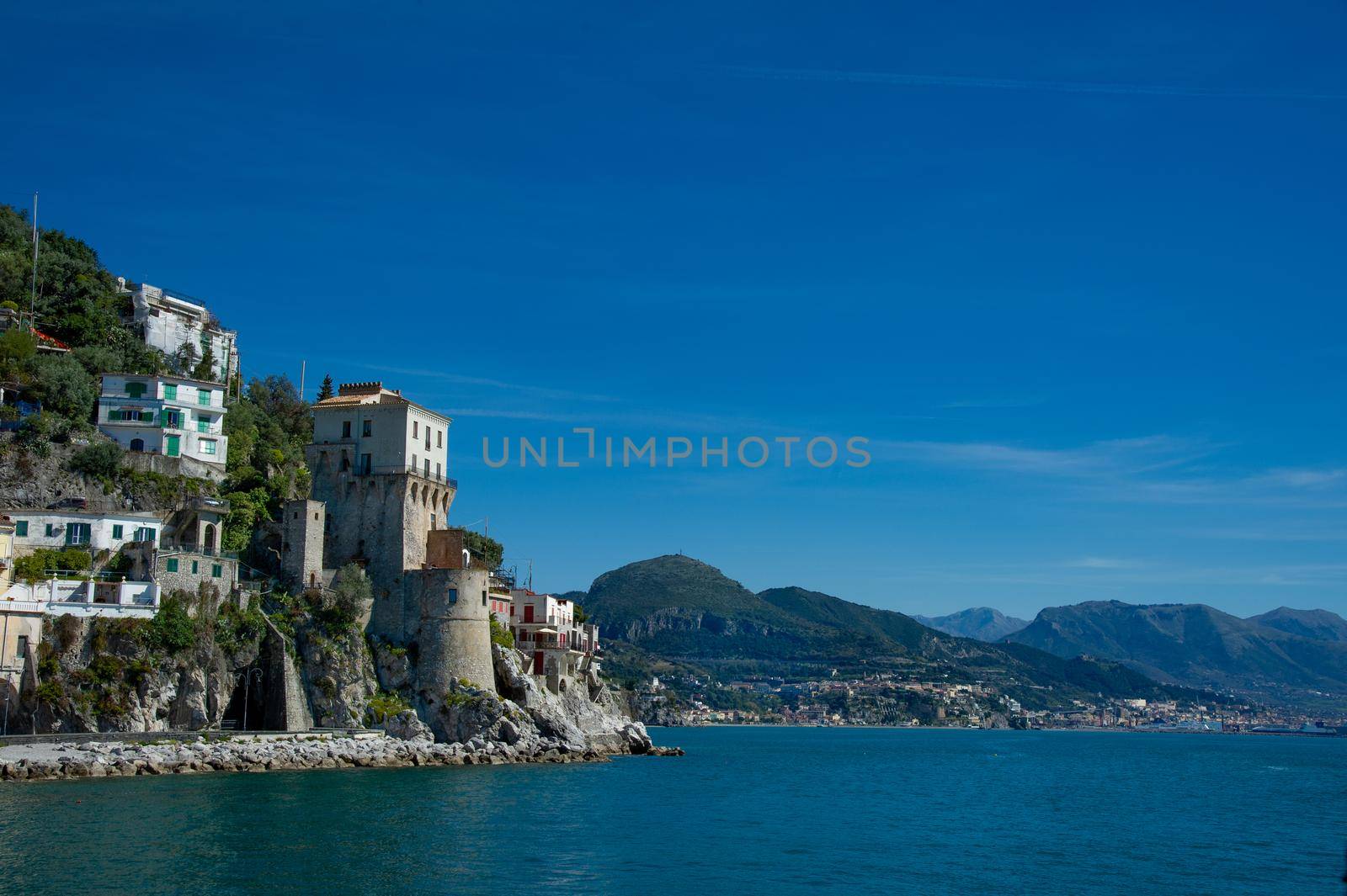 Beautiful view, of small haven of Amalfi village with small beach and colorful houses located on rock. Tops of mountains on Amalfi coast, Salerno, Campania, Italy blue sky and beautiful weather