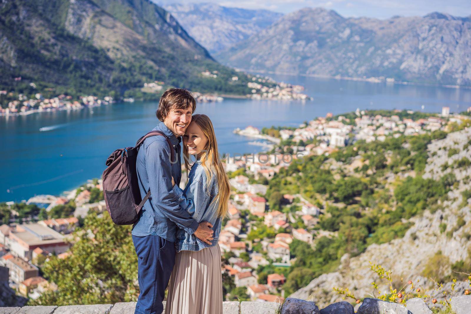 Couple woman and man tourists enjoys the view of Kotor. Montenegro. Bay of Kotor, Gulf of Kotor, Boka Kotorska and walled old city. Travel to Montenegro concept. Fortifications of Kotor is on UNESCO World Heritage List since 1979.