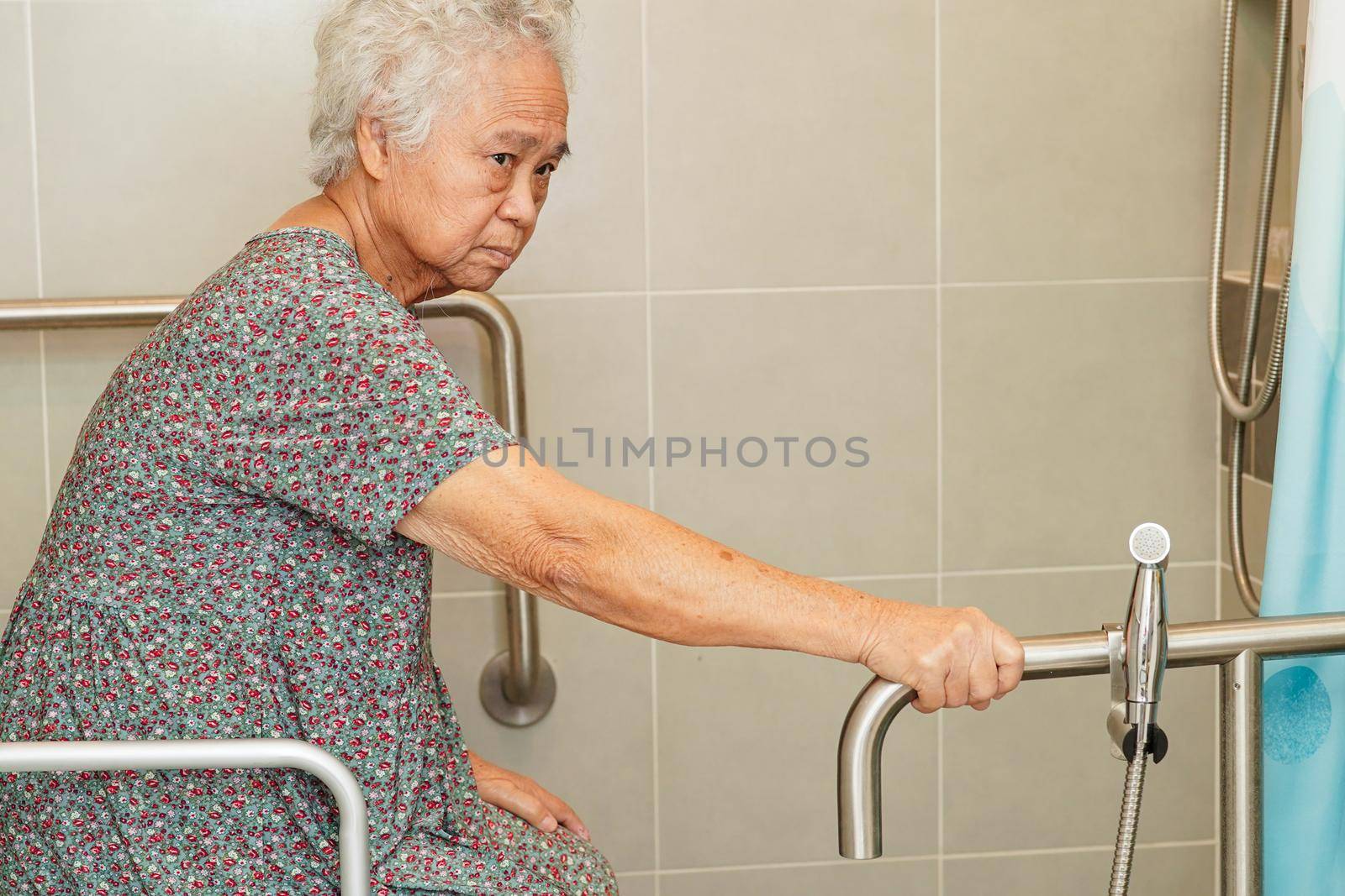 Asian elderly old woman patient use toilet support rail in bathroom, handrail safety grab bar, security in nursing hospital.