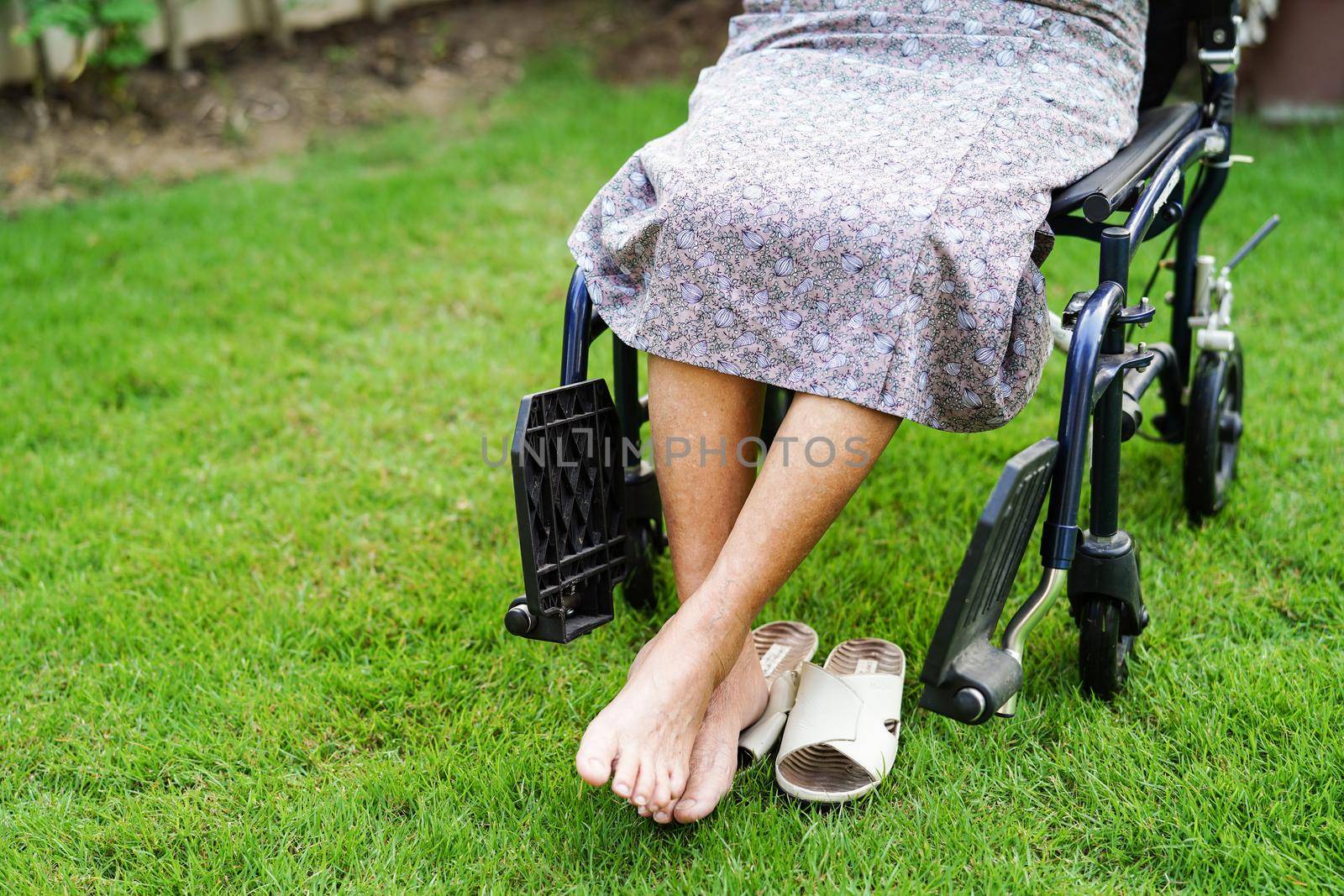 Asian elderly woman disability patient sitting on wheelchair in park, medical concept.