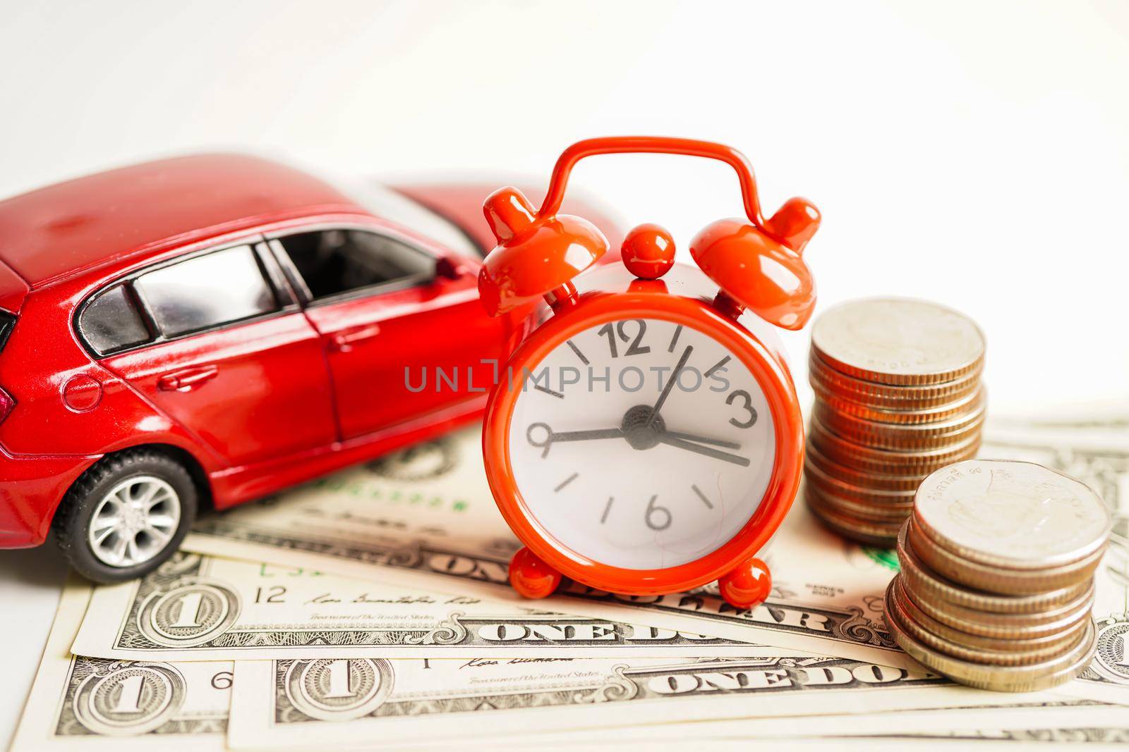 Car on coins money with alarm clock, saving bank, finance, installment payment, car loan interest.