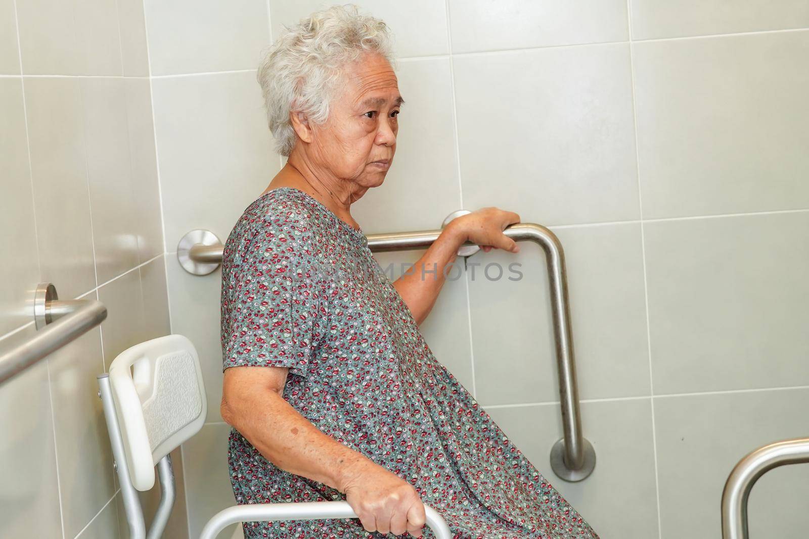 Asian elderly old woman patient use toilet support rail in bathroom, handrail safety grab bar, security in nursing hospital.