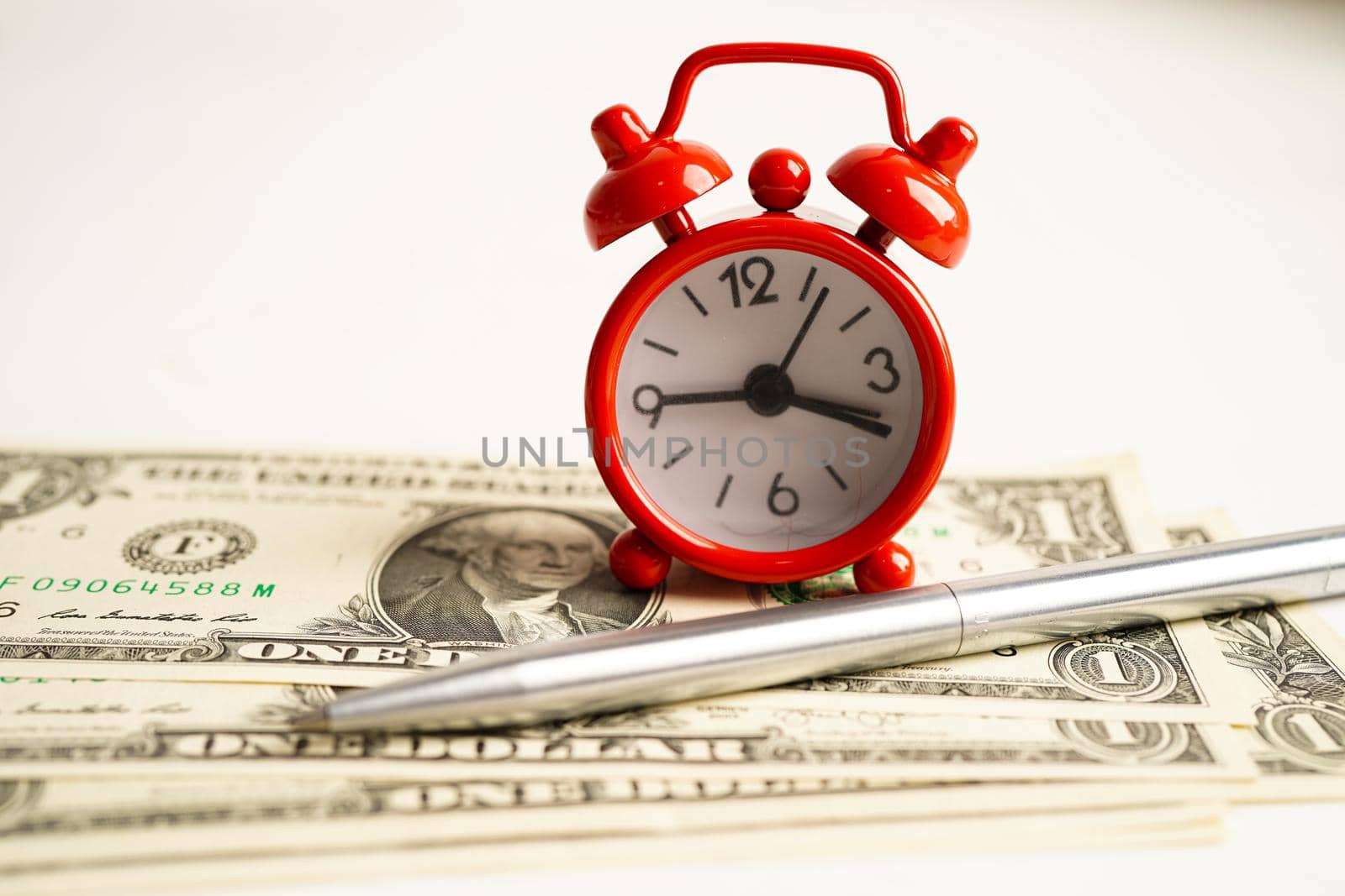 Alarm clock with coins on US dollar banknotes, finance installment loan time.         