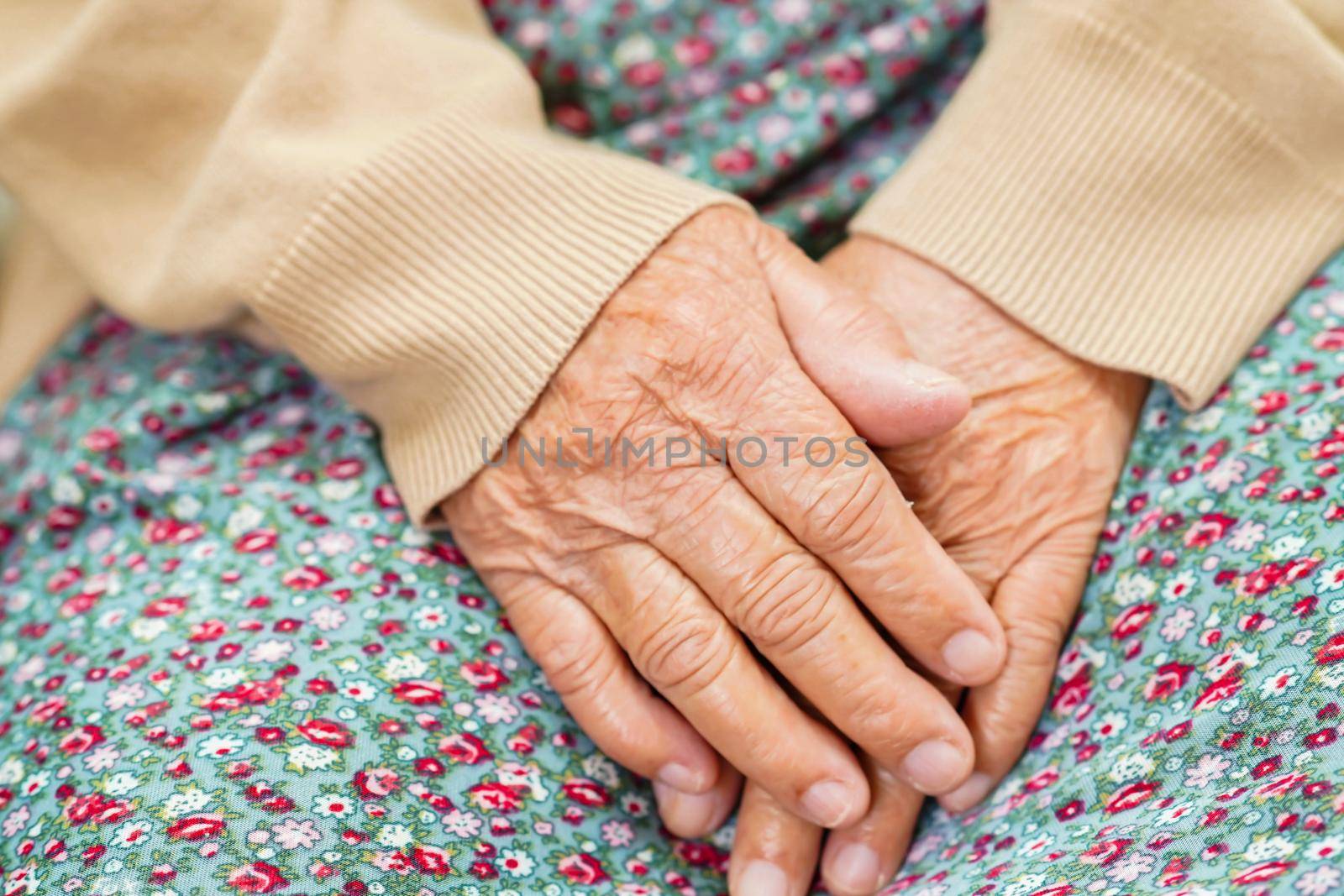 Asian elder senior woman patient sitting on bed in hospital, closeup at her hand.