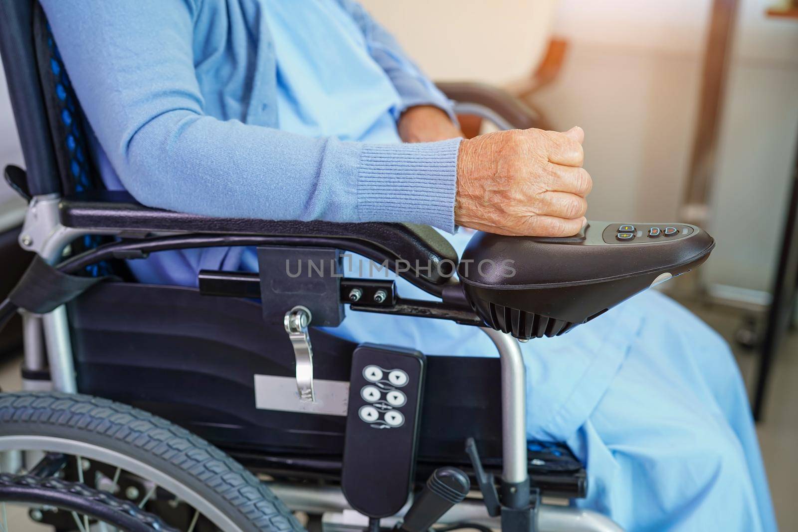 Asian elderly woman disability patient sitting on electric wheelchair in park, medical concept.