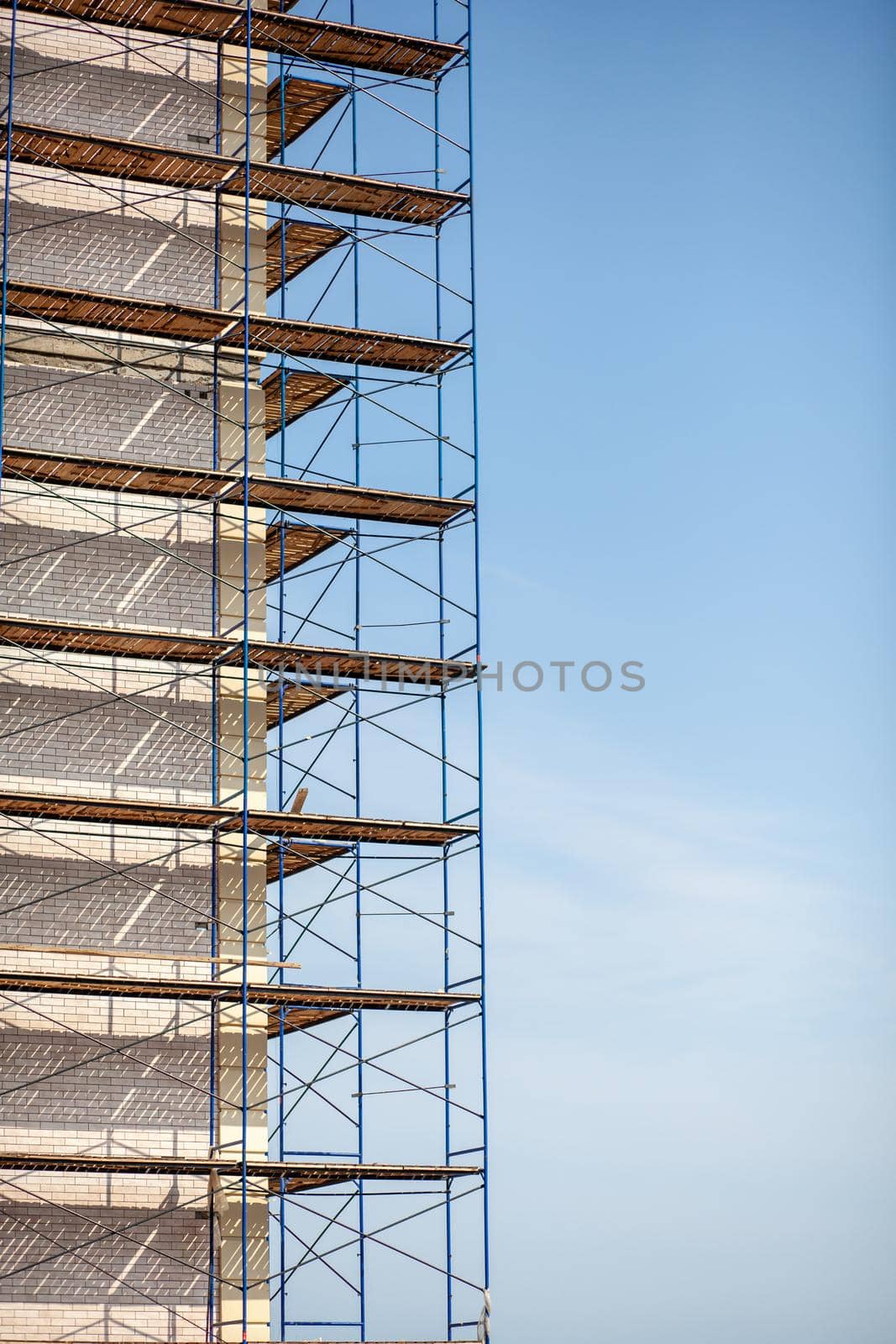 Scaffolding, metal mobile scaffold aginst blue sky background. Modern building is under construction, metal scaffolding.