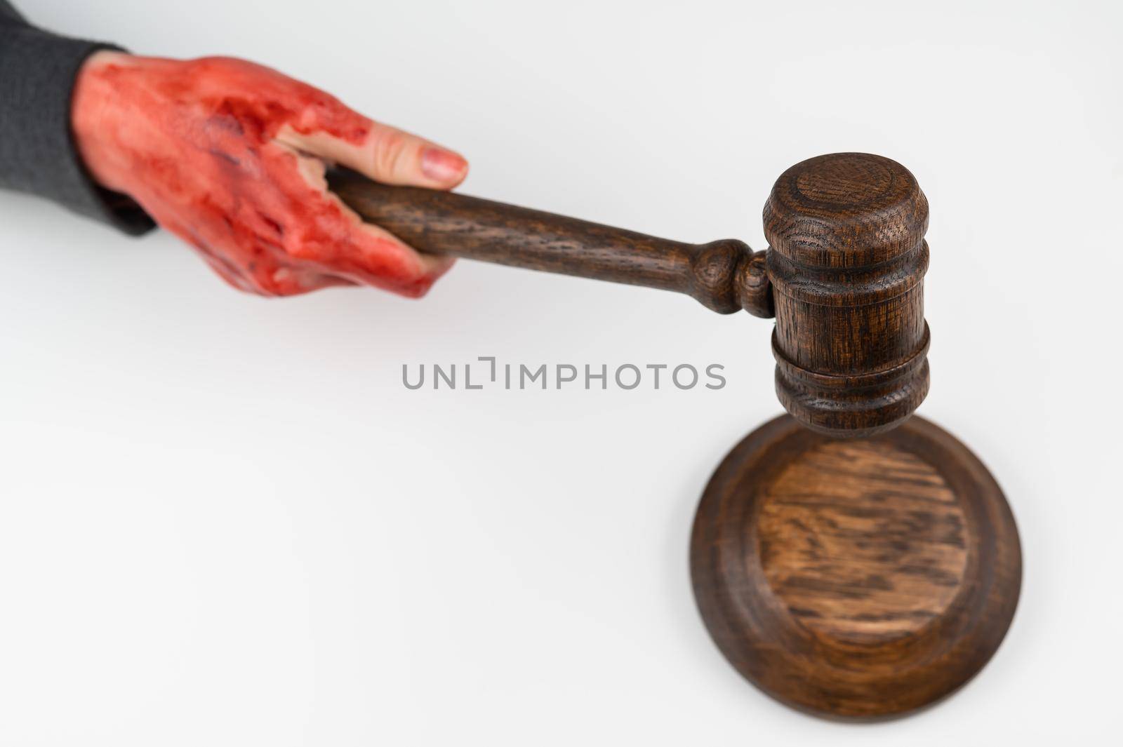 Female judge with bloody hands beats the gavel on a white background. by mrwed54