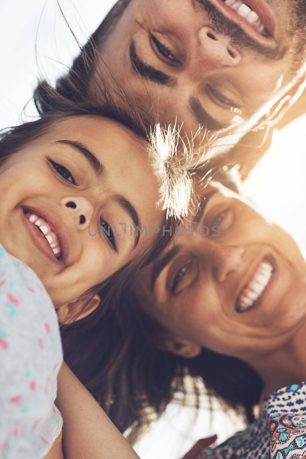 Theres nothing quite like family. Low angle portrait of a happy young family enjoying their day at the beach. by YuriArcurs