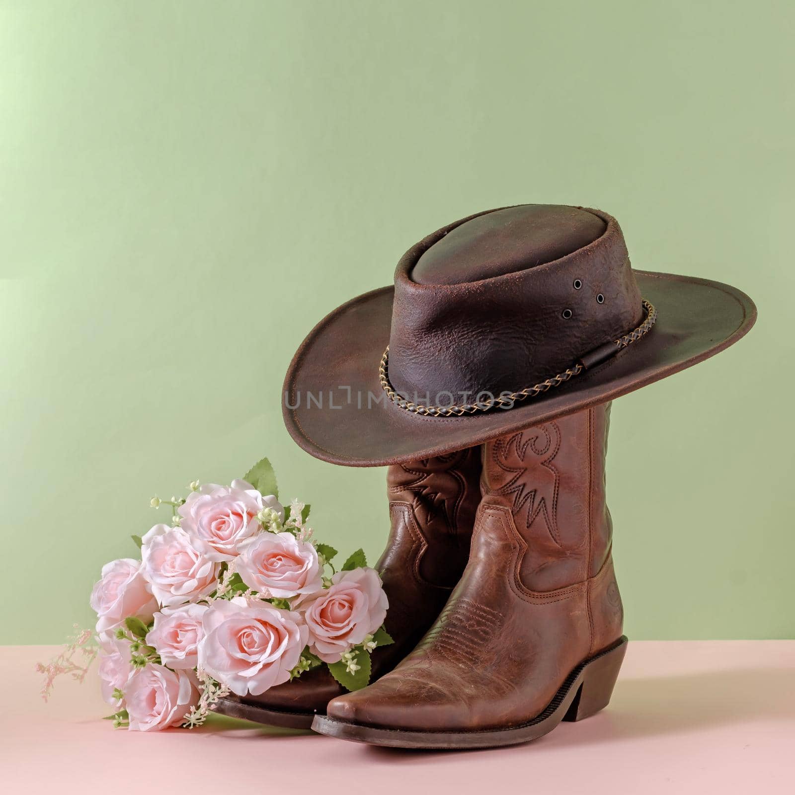 Cowboy boots shoes and hat and bouquet of rose flowers on green background by sergii_gnatiuk