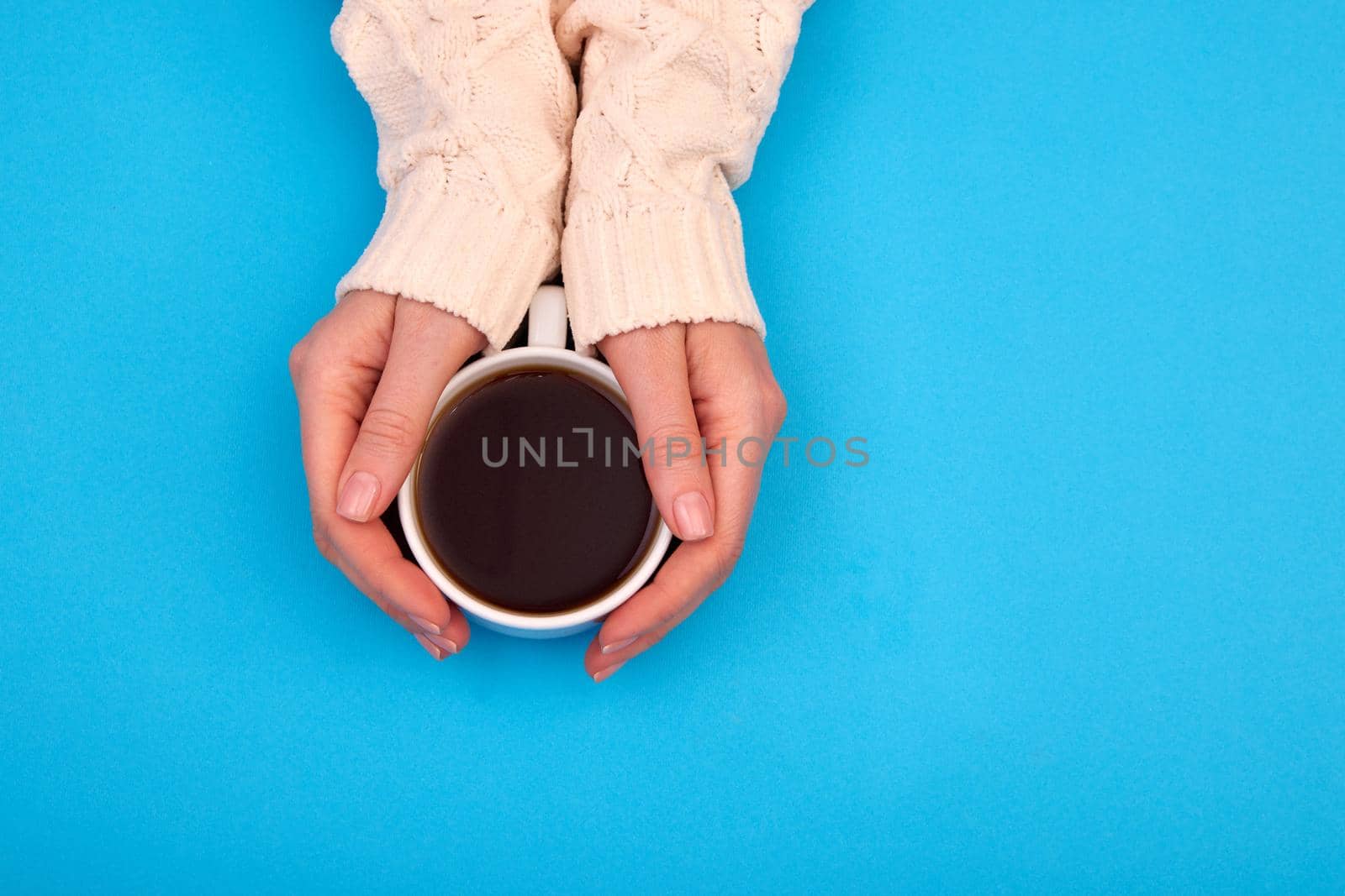 Woman with a cup of tea in her hands view from above blue background