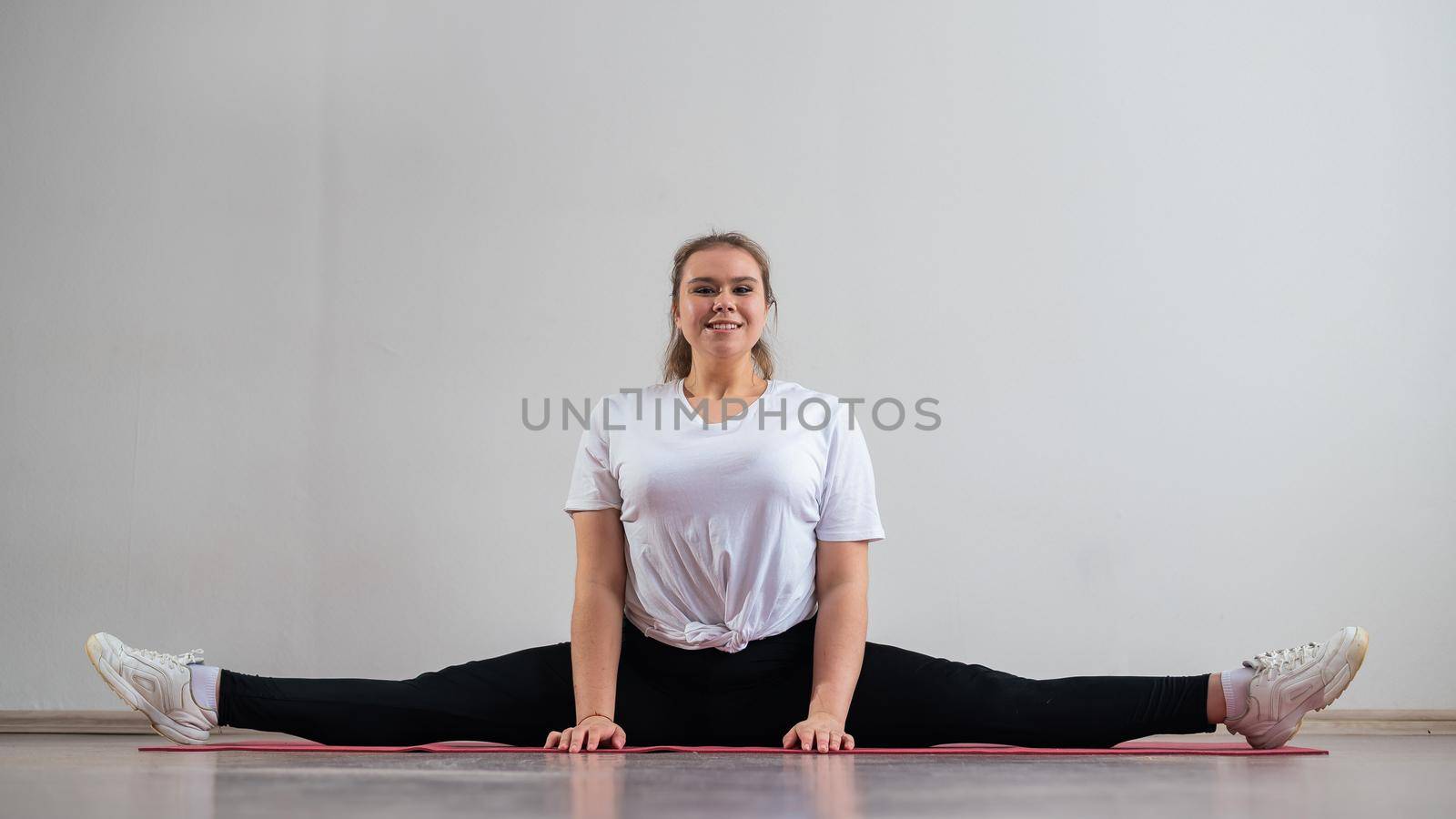 Chubby young woman doing stretching on white background. by mrwed54