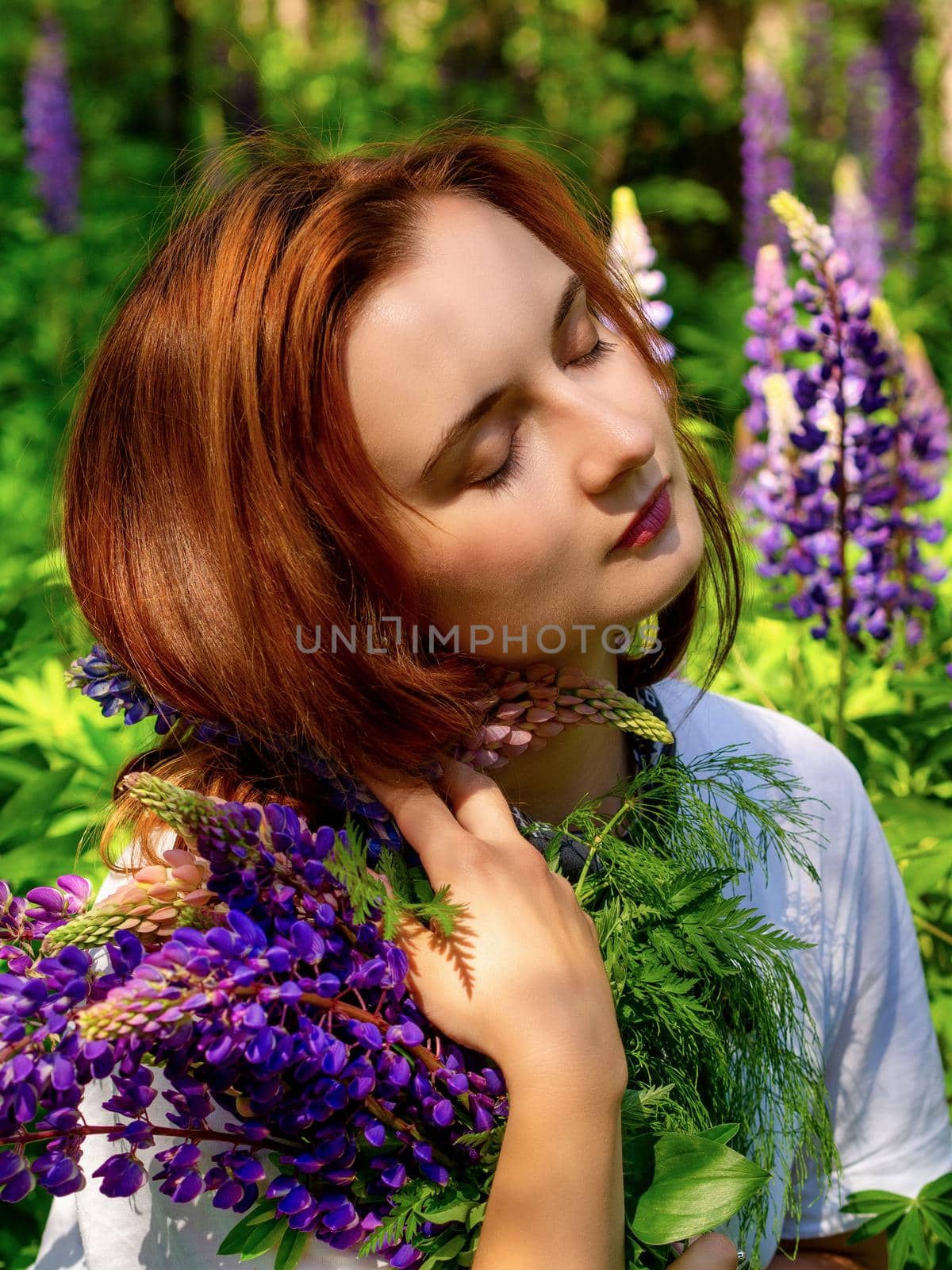 Young caucasian woman in nature among the flowers of blooming lupine. photo