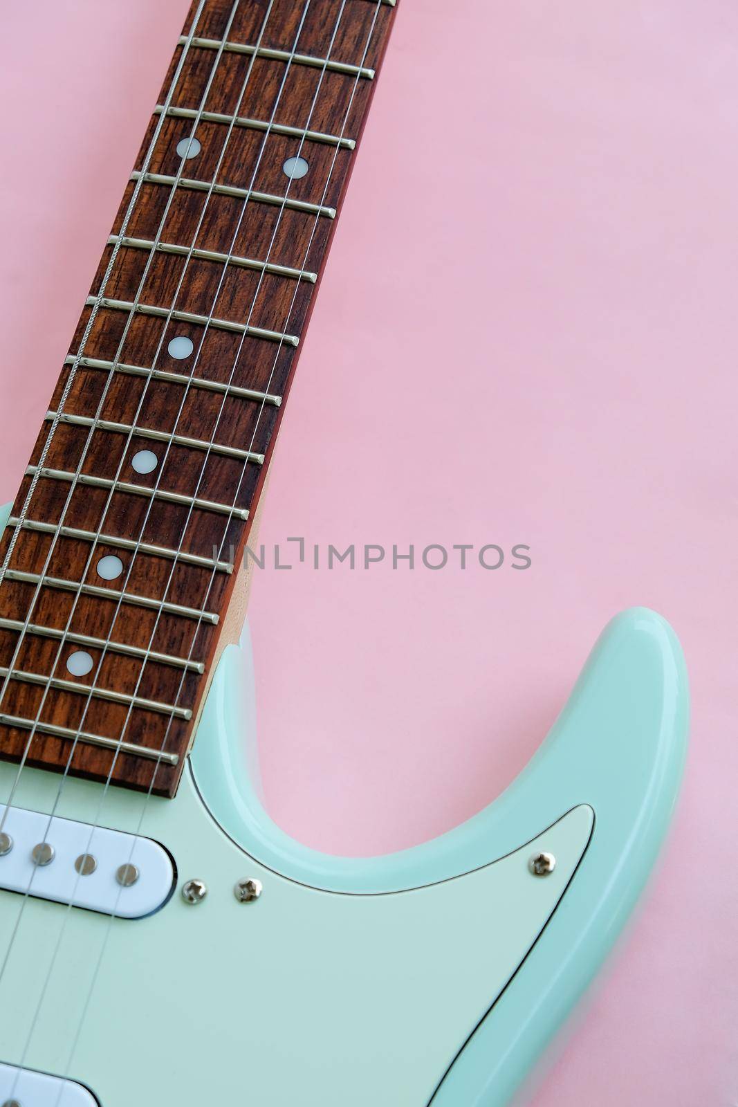 Detail of Mint Green Electric Guitar on a Pink background.