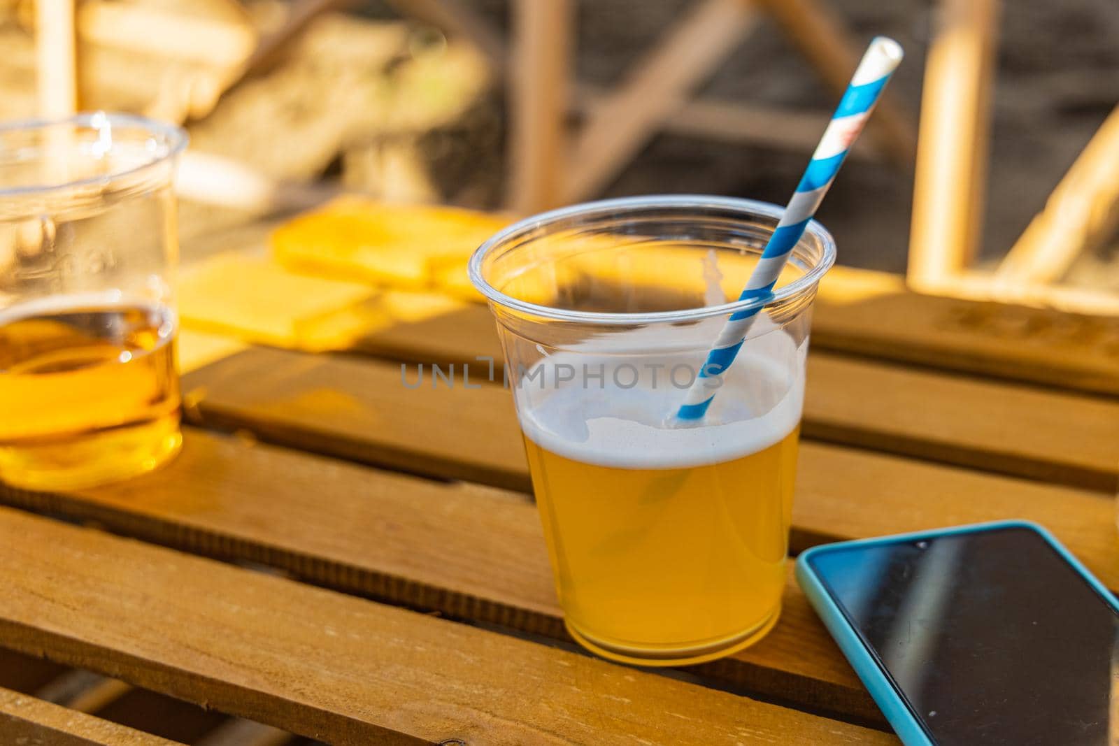 Beers with colorful straw and smartphone lie on wooden table made from crate by Wierzchu