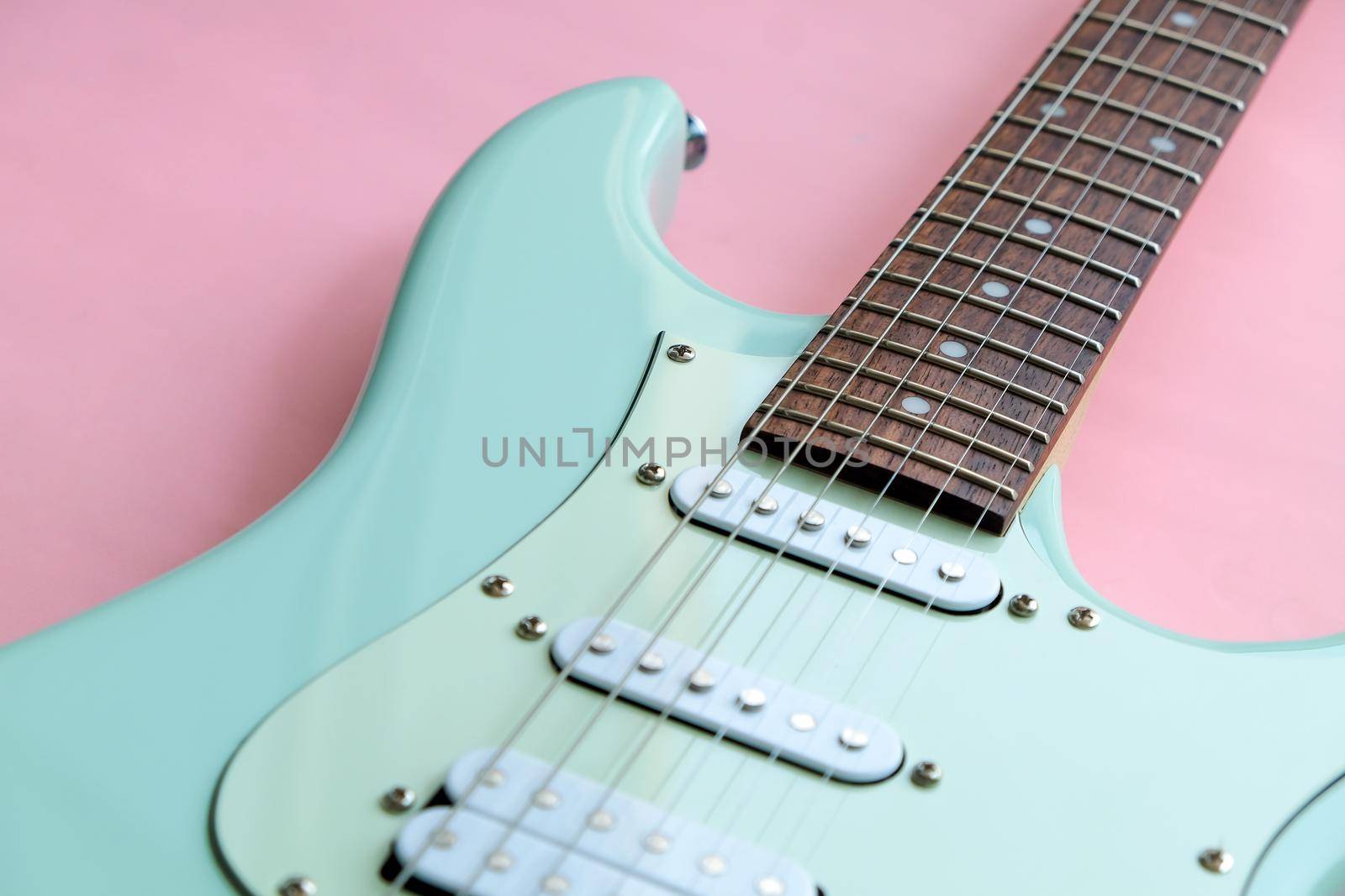 Detail of Mint Green Electric Guitar on a Pink background.
