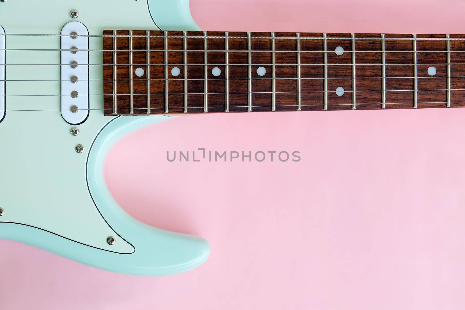 Detail of Mint Green Electric Guitar on a Pink background.