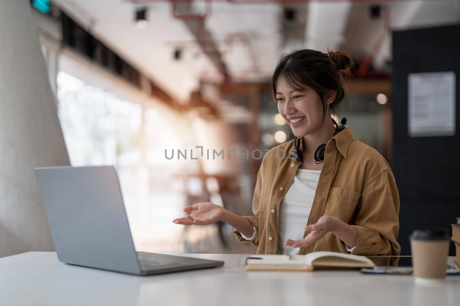 smiling asian woman freelancer wearing headset, communicating with client via video computer call. Millennial pleasant professional female tutor giving online language class. by nateemee