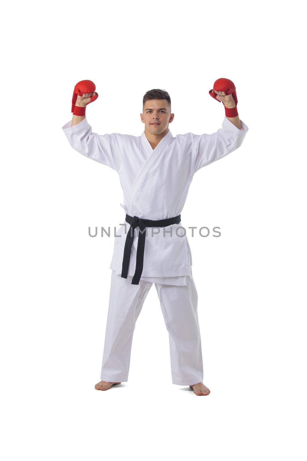 Full length portrait of a fighter man winner in karate kimono holding isolated on white background