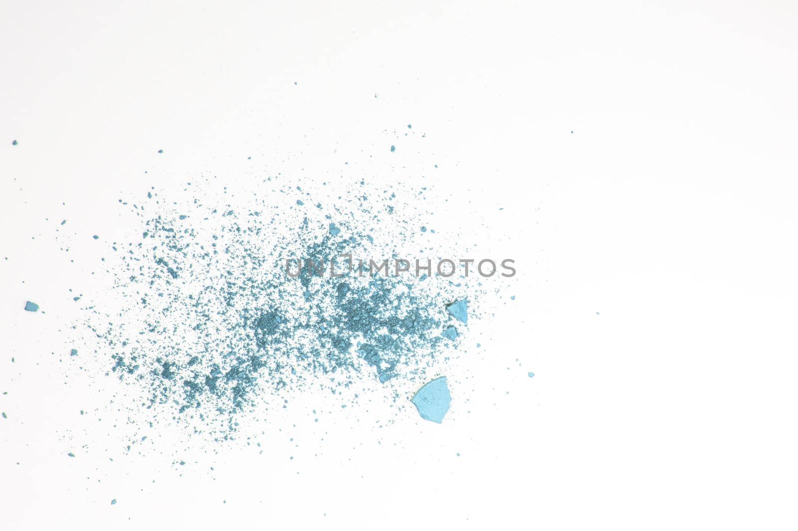 Broken and crumbled blue eye shadow isolated on white background, make-up concept.