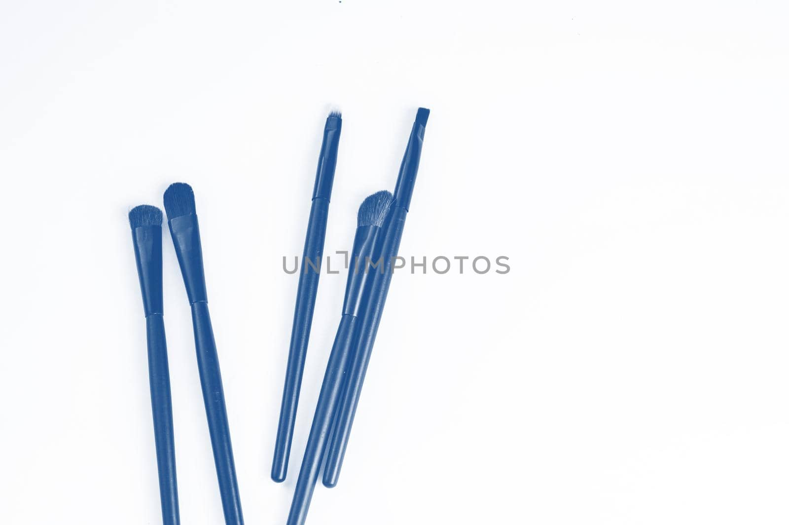 A set of makeup brushes isolated on a white background, a classic blue tinting color, a copy of the space, the concept of care and beauty of makeup.