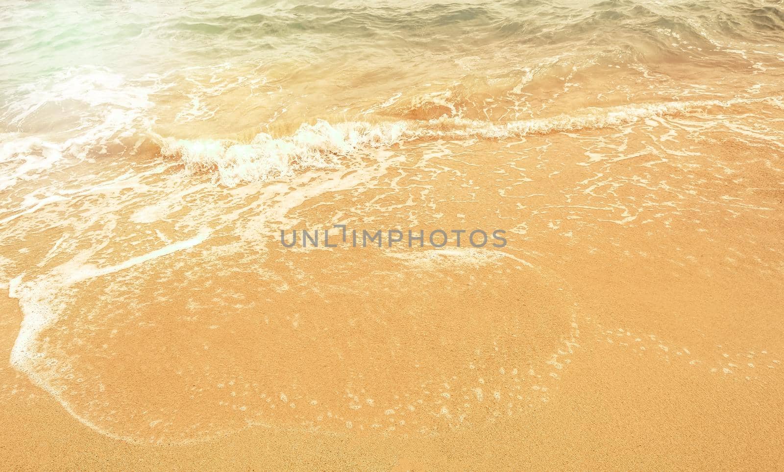 Magnificent summer sea abstract beach background with Golden sand, white foam, blue ocean and sunlight.