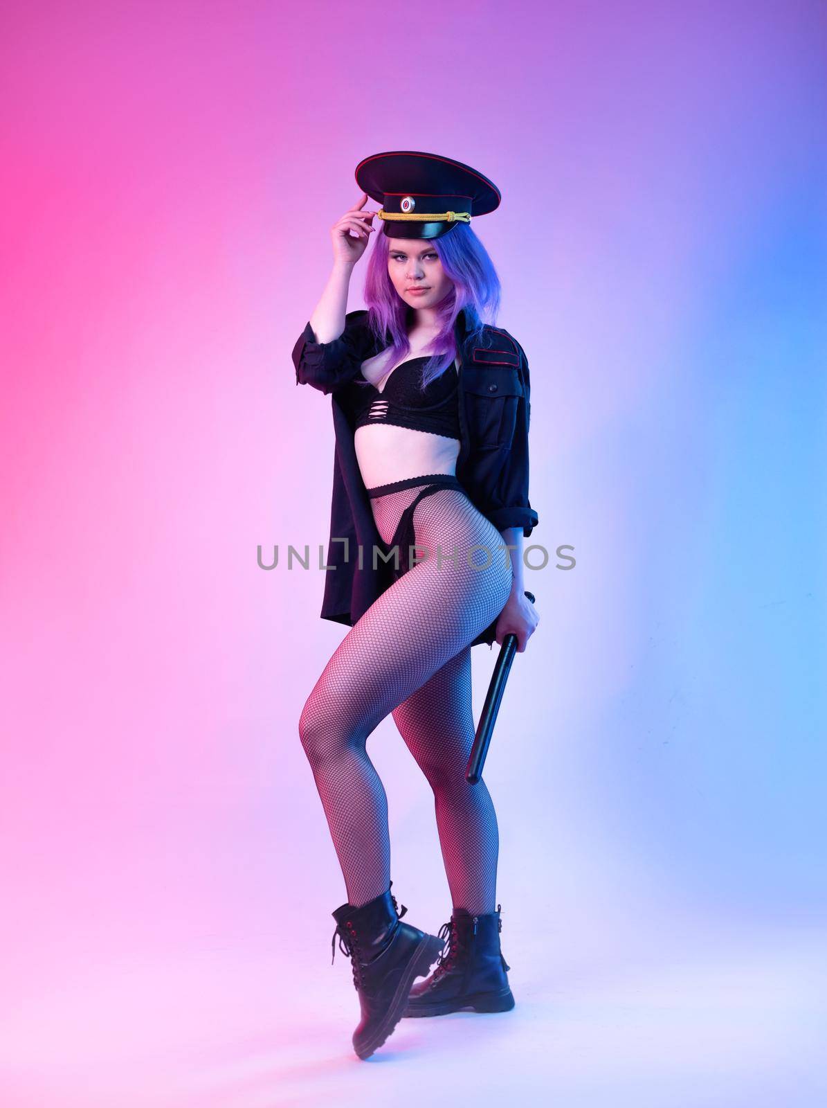 Sexy girl in police uniform posing in underwear with a police rubber baton in neon light by Rotozey