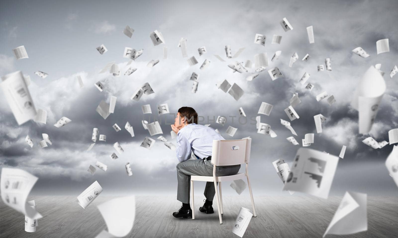 young businessman sits on an office chair, thoughtful and looking up