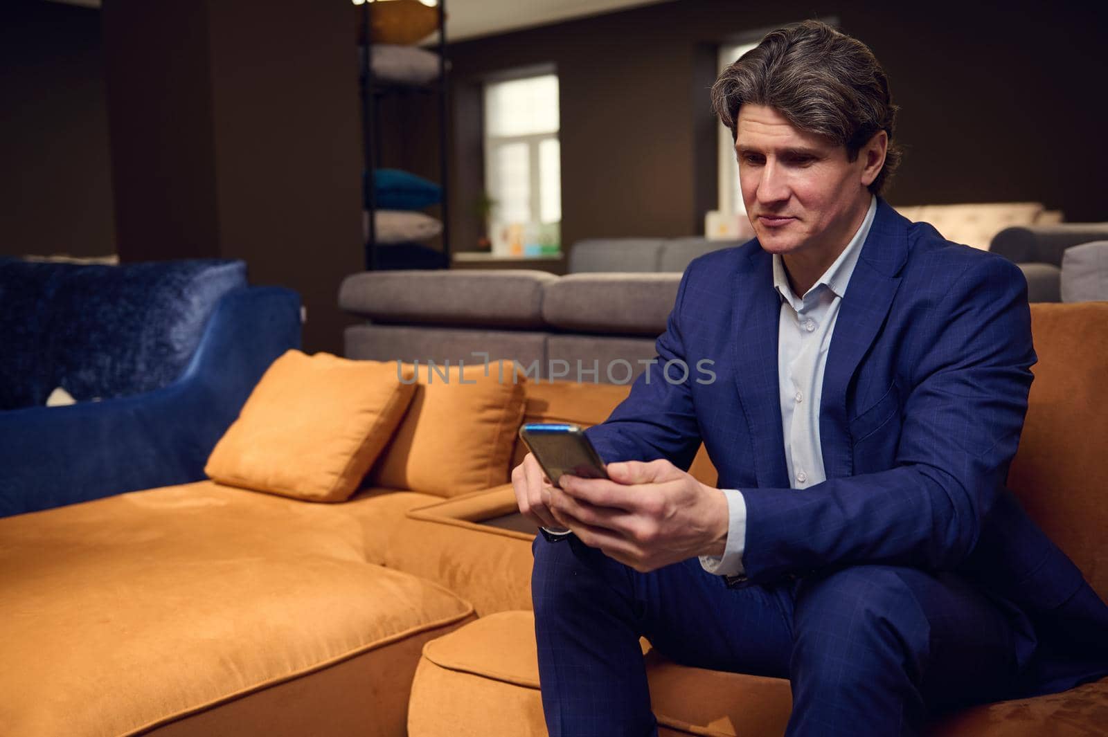 Mature Caucasian man, businessman, entrepreneur, sales rep, retail manager holding a mobile phone, typing text messages, surfing, browsing, swiping websites. Business, internet, communication concept