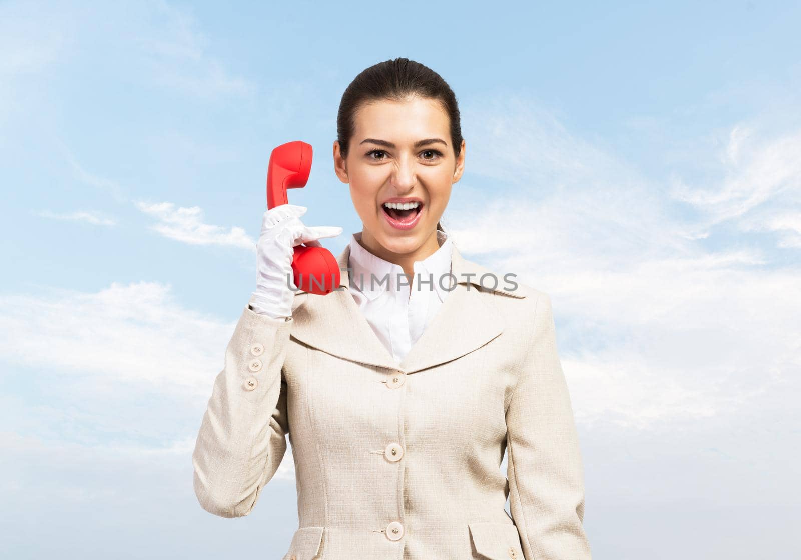 Expressive woman shouting into red handset phone. Operator in business suit standing with cellphone on blue sky background. Business assistance and consultation. Customer service support concept