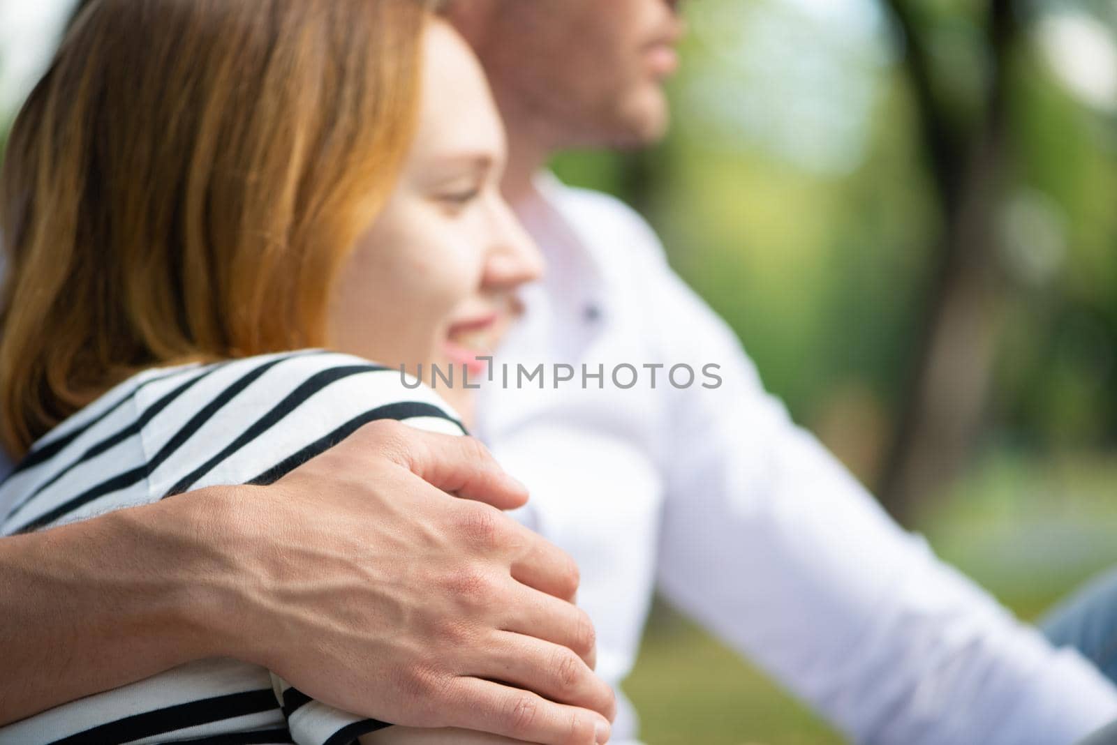 A young man hugs a woman. Sitting hugging in the park
