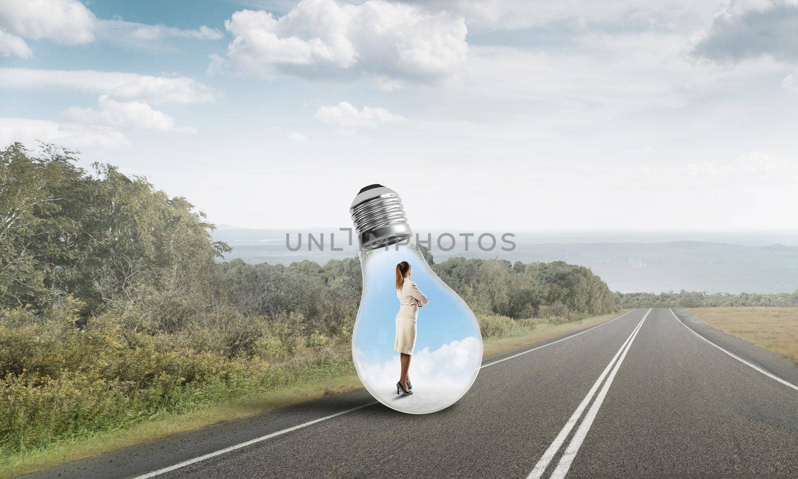 Young businesswoman trapped inside of light bulb on asphalt road