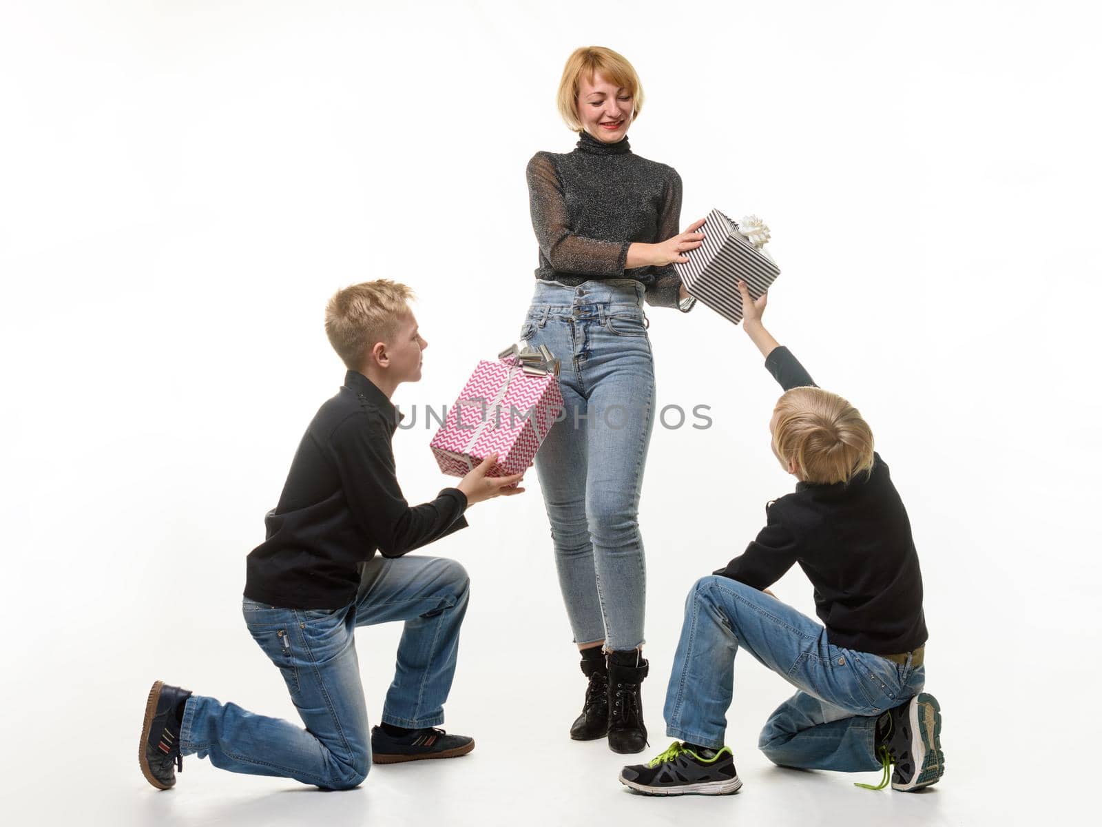 Children give a gift to mom, kneeling, mom picks up one of the gifts, white background
