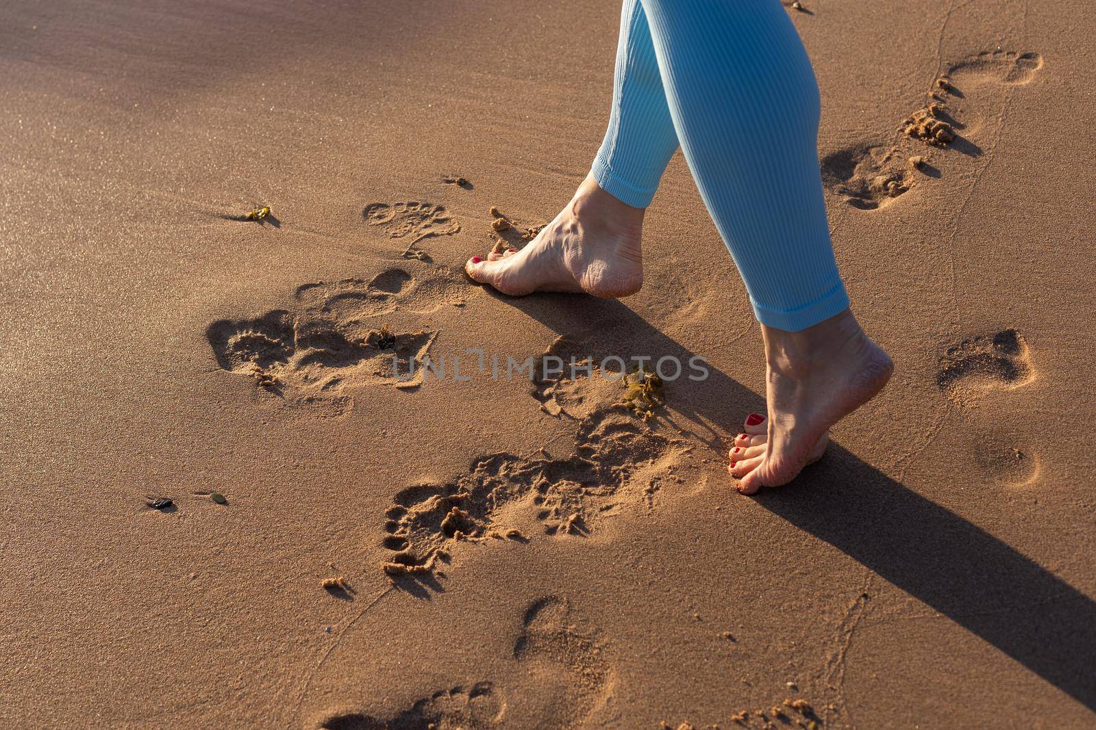 Close up woman legs walking on tropical sunset beach with smooth wave and bokeh sun light wave abstract background. Travel vacation and freedom feel good concept. Vintage tone filter color style. by Andelov13
