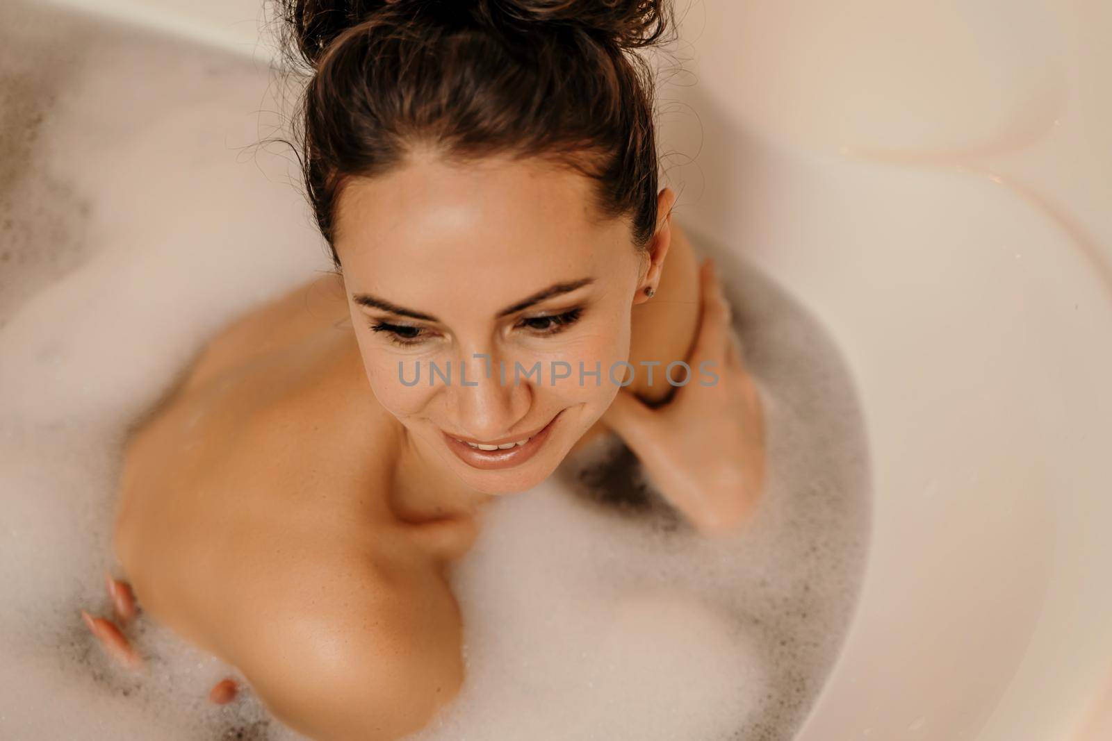 Close up relaxed woman lying in bath foam at bathroom. Romantic girl relaxing at bathtub at home. Close up sexy woman taking bath indoors