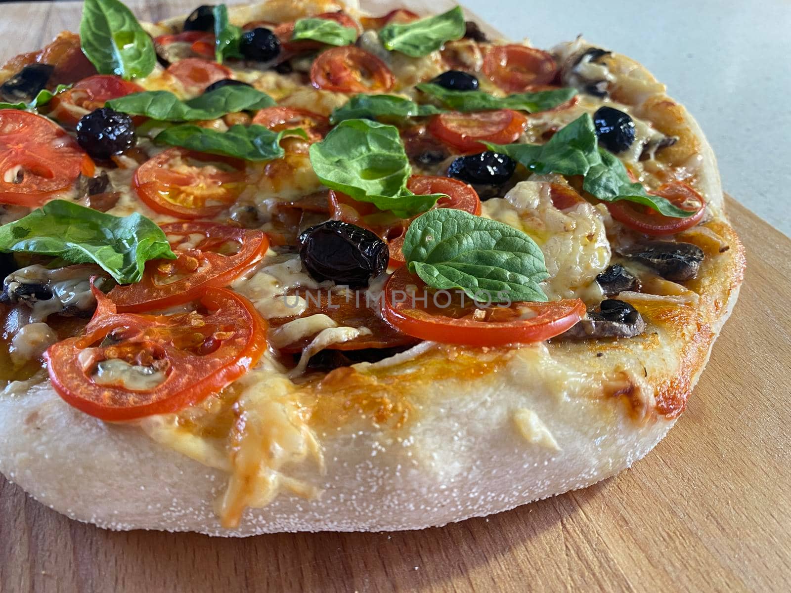 Delicious freshly baked pizza, just out of the oven on a wooden board.
