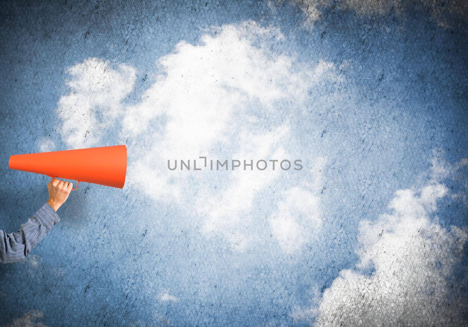 Hand of man holding paper trumpet against blue concrete background by adam121