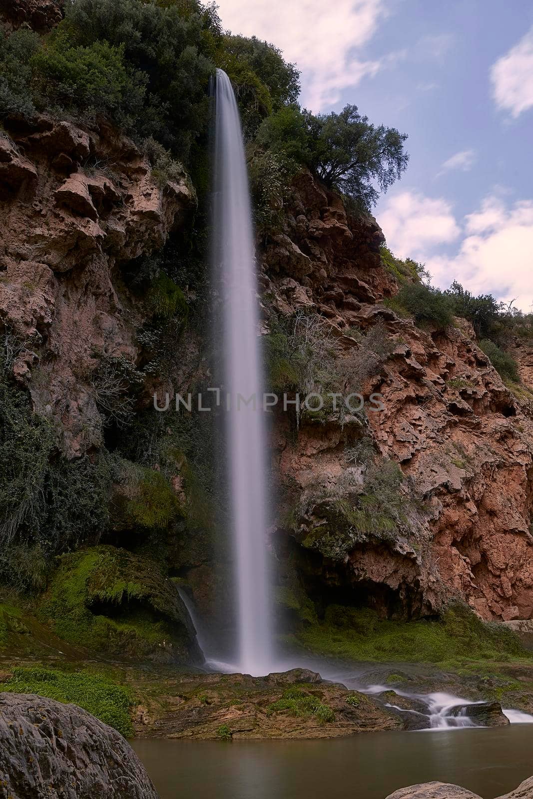 A large waterfall on a sunny dayFront view, long exposure, silk effect water. Bride jumping