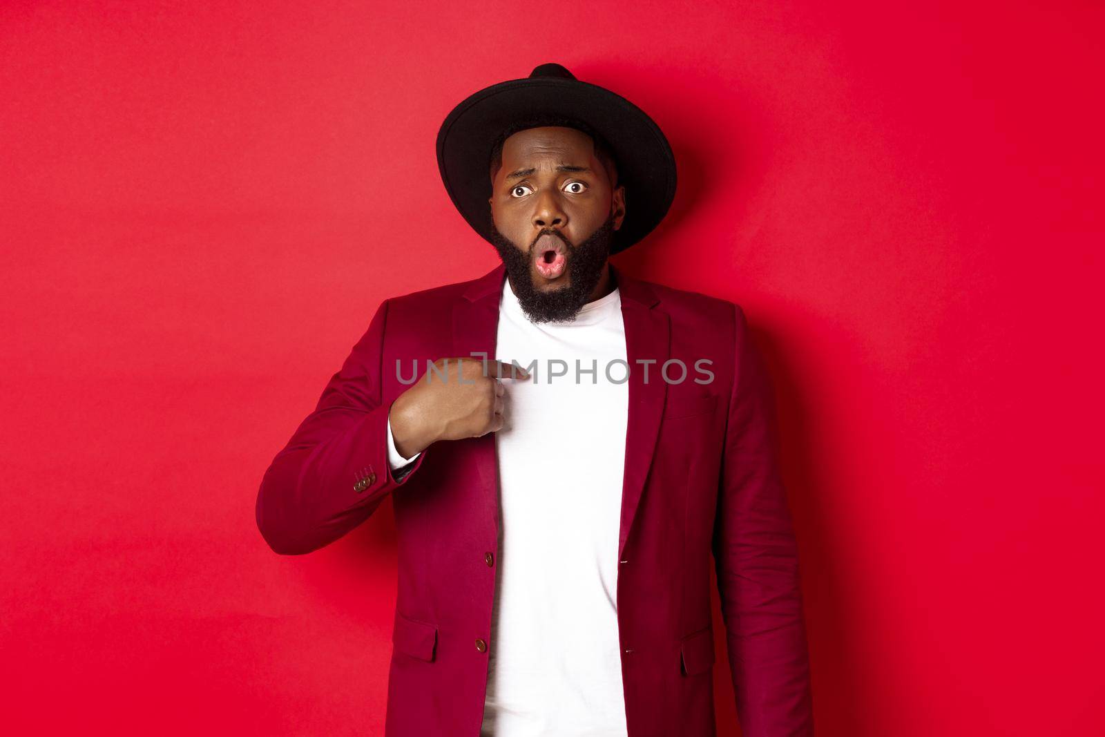 Christmas shopping and people concept. Worried african american man pointing at himself, being accused, standing nervous against red background by Benzoix