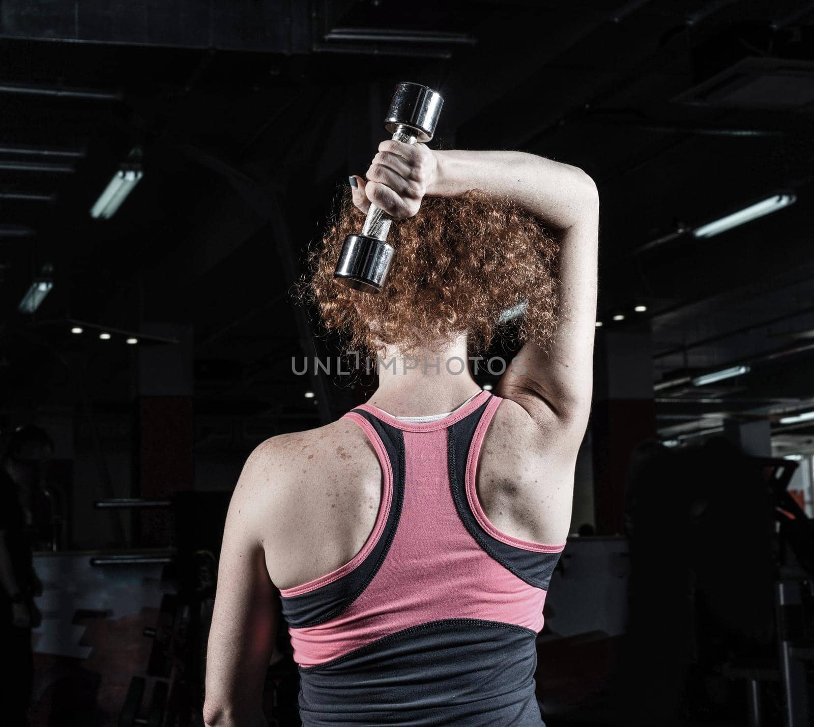 Woman bodybuilder engaged with dumbbells in the gym.