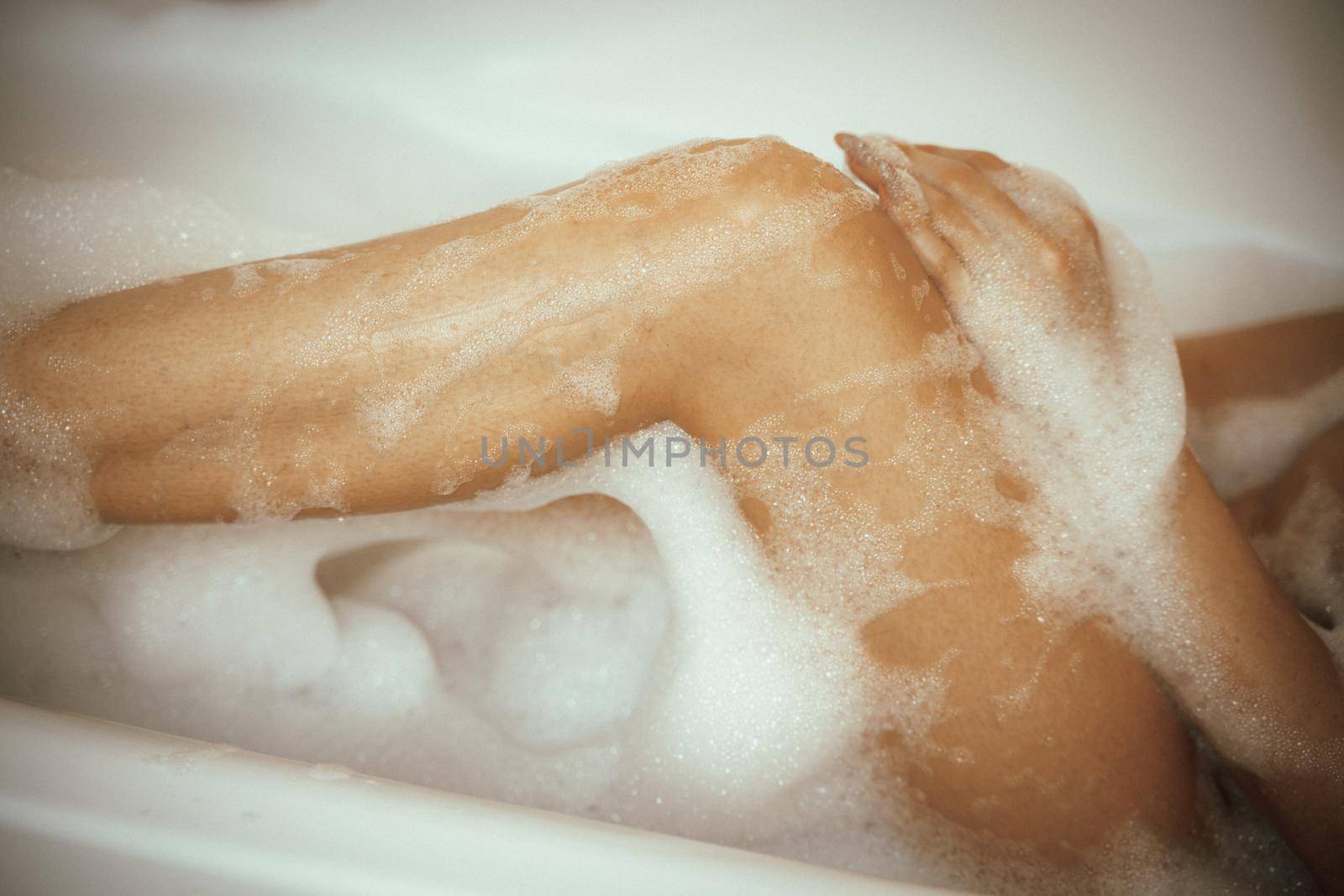 Women's feet in bath foam. View from above. Enjoy and relax in a spa hotel.