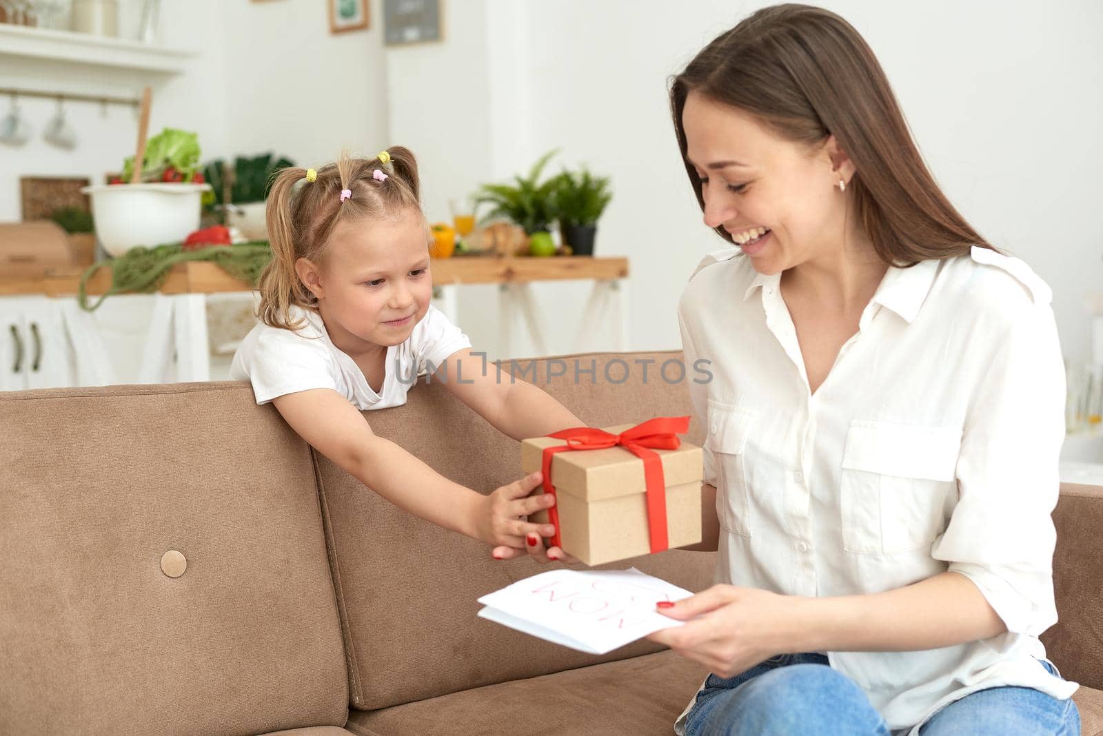 Lovely little girl gives her mom a card and a gift for March 8 or mother's day. Loving family concept. by etonastenka