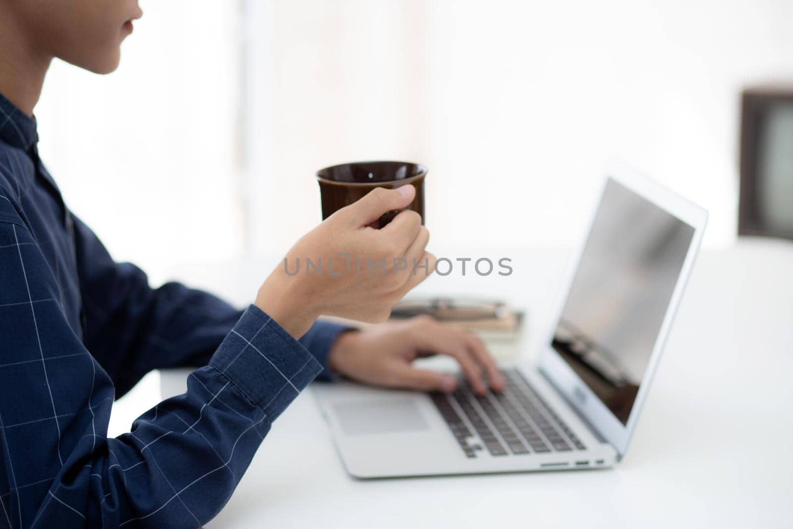 Young business man working from home with laptop computer on desk, freelance male sitting stay home using notebook for communication and relax on table, entrepreneur in startup business, new normal. by nnudoo