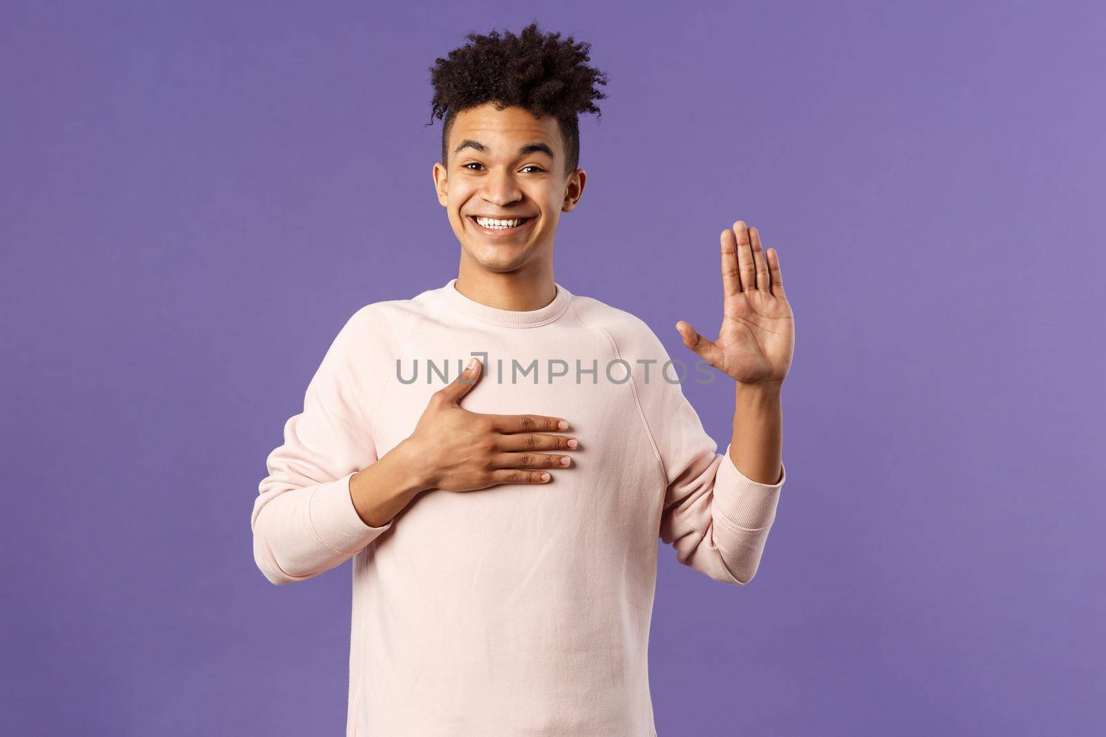 Portrait of young happy, joyful hispanic man making honest statement, promise to tell only truth, hold one hand on heart and another raised, smiling sincere, standing purple background by Benzoix