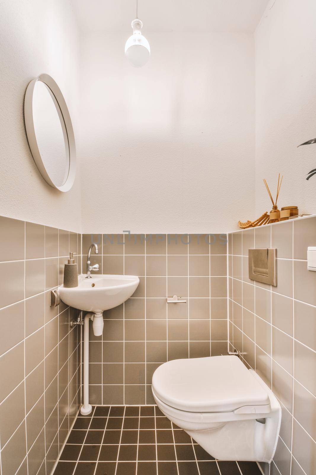 Toilet with brown tiles decoration, round mirror and white wall