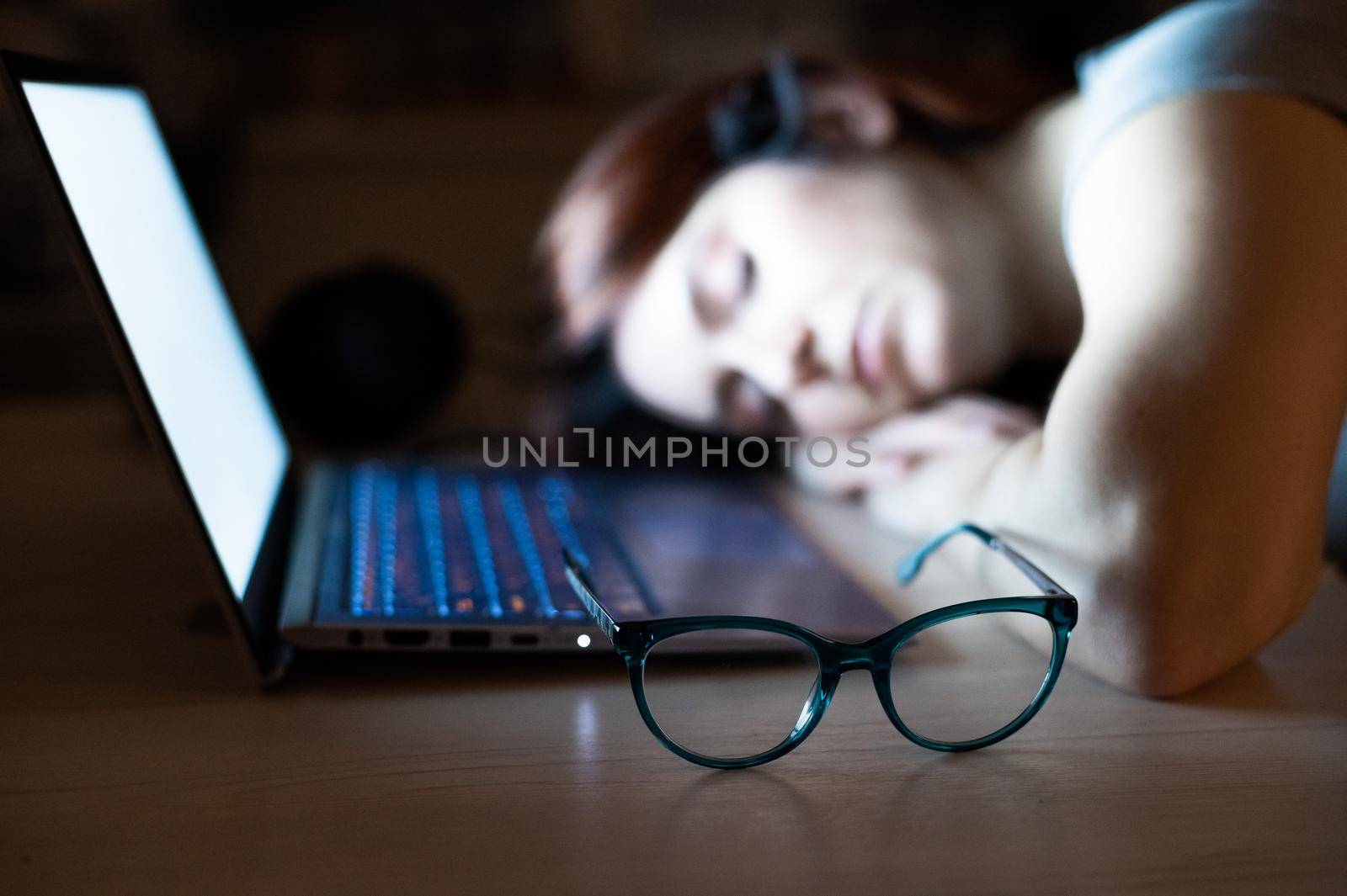 The exhausted employee worked overtime and fell asleep at his desk. Deadline Work at night with a laptop. The student is preparing for the exam